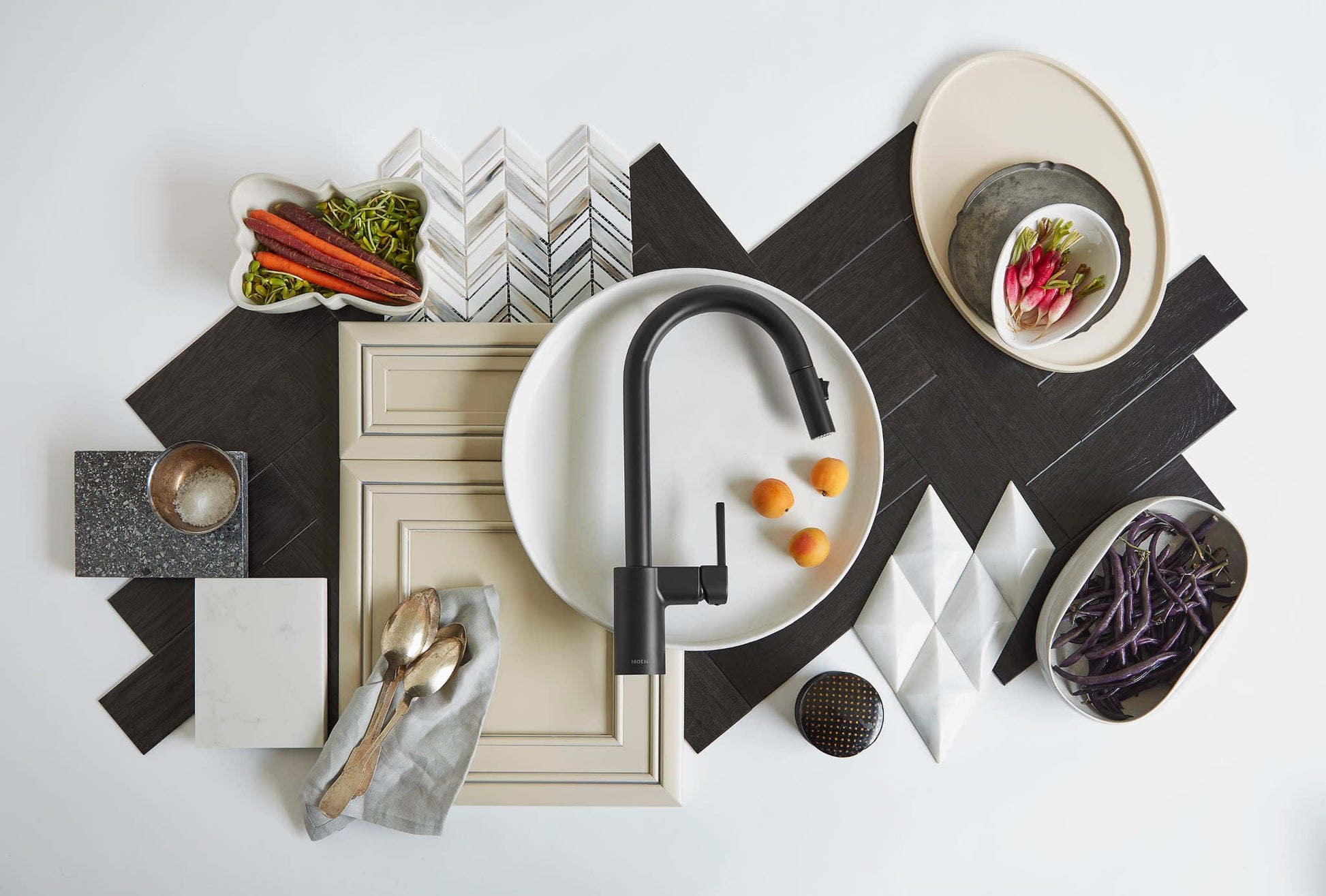 Matte black high-arc pulldown kitchen faucet with single handle displayed above white sink basin surrounded by styling elemen
