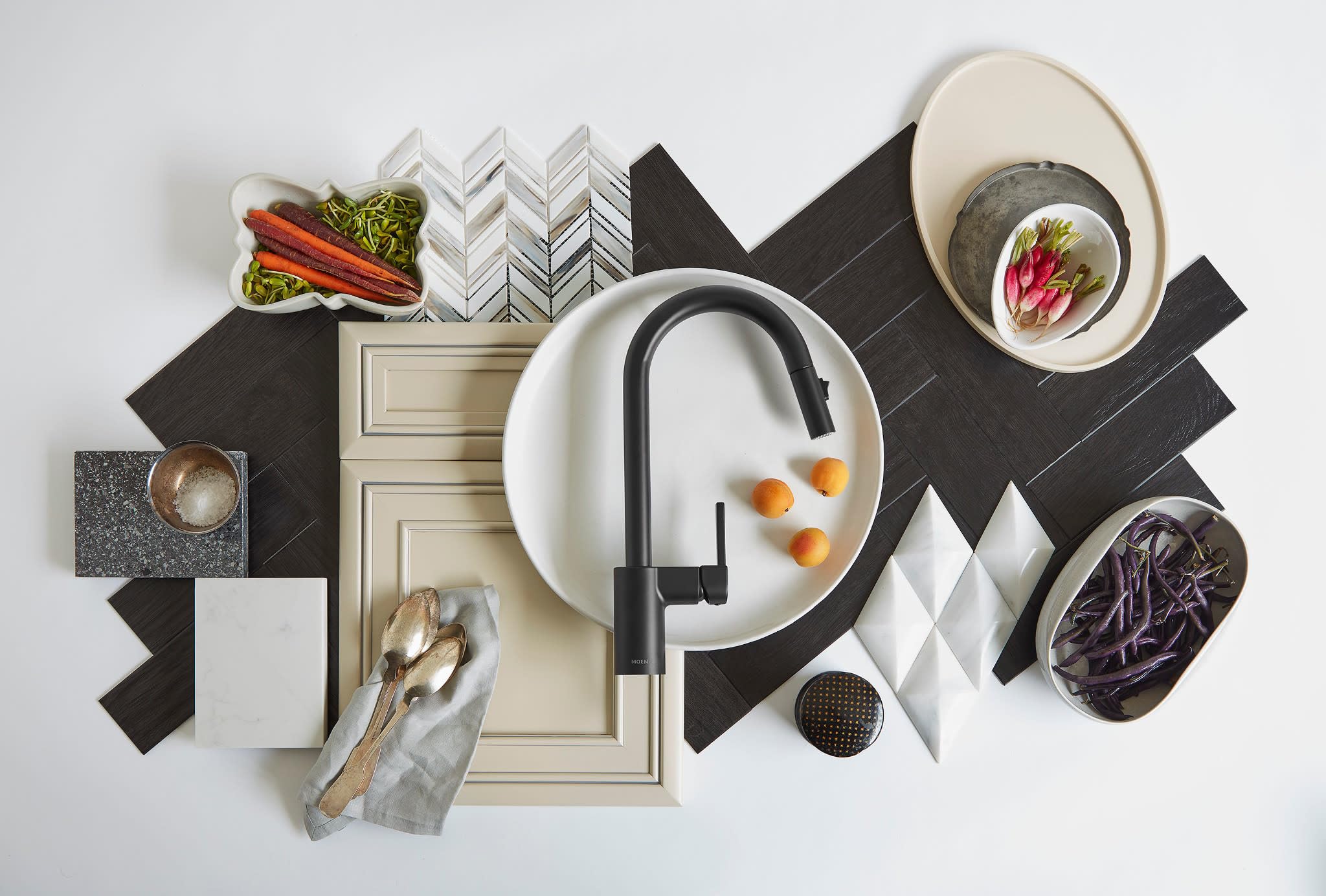 Matte black high-arc pulldown kitchen faucet with single handle displayed above white sink basin surrounded by styling elemen