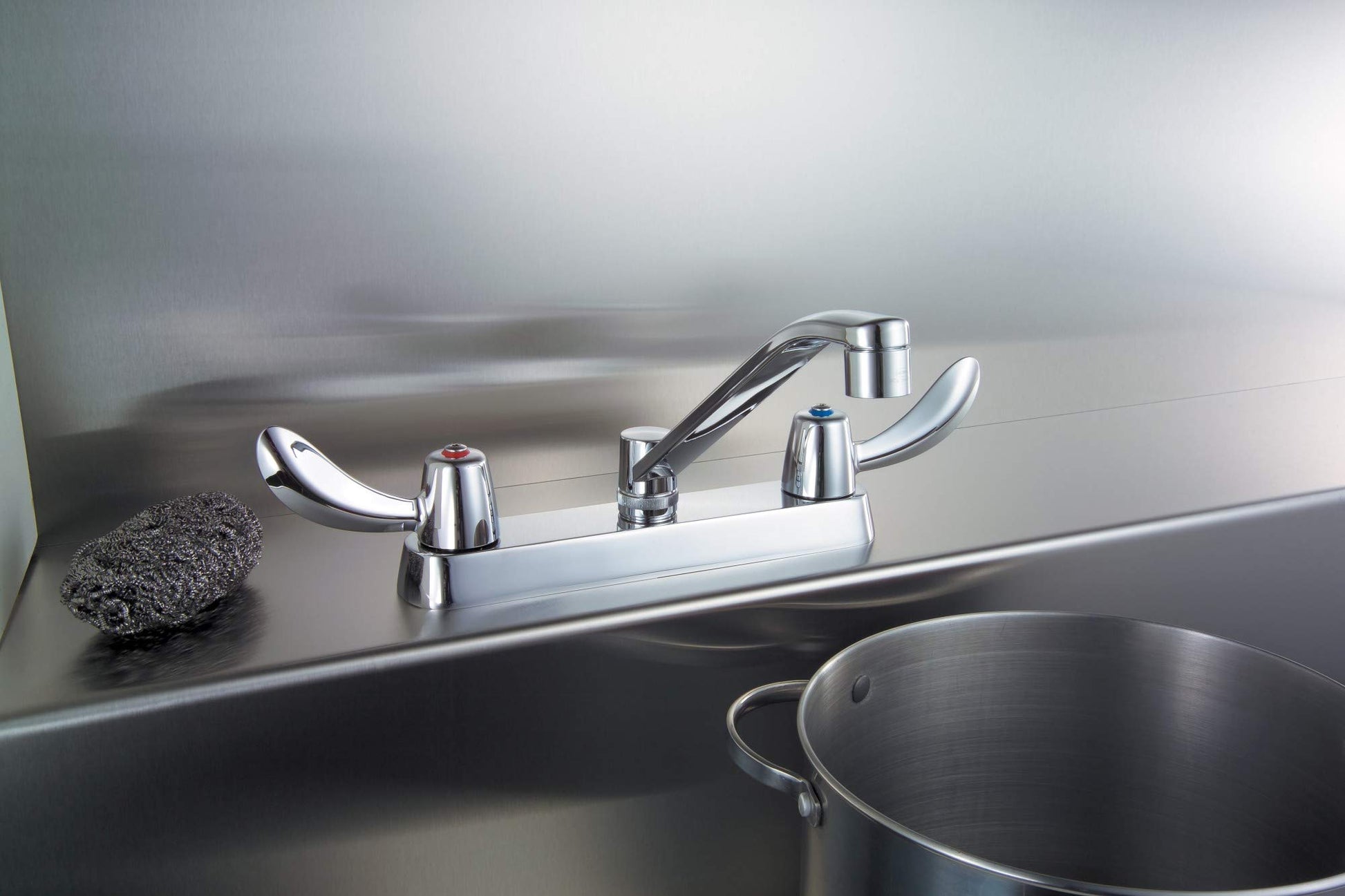 Chrome two-handle deck mount faucet with curved spout installed on stainless steel sink rim.