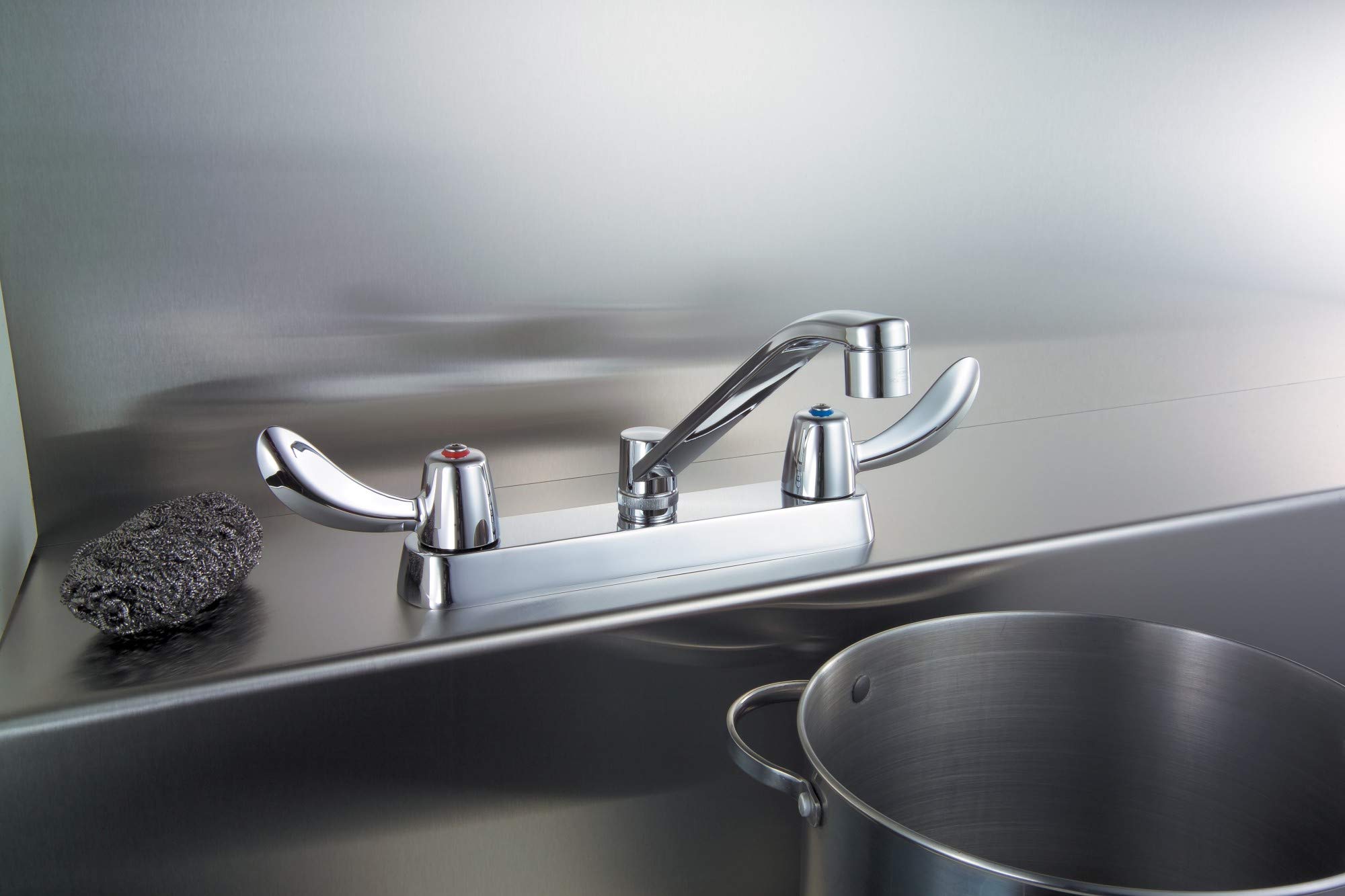 Chrome two-handle deck mount faucet with curved spout installed on stainless steel sink rim.