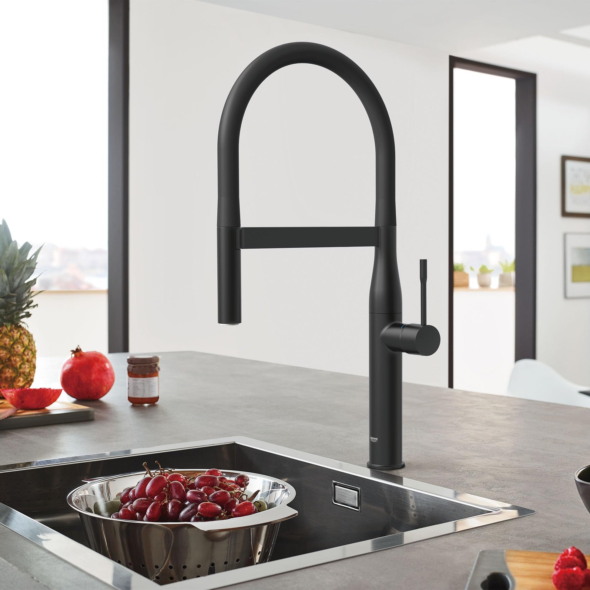 Matte black single-handle kitchen faucet with high arched spout and pull-down spray head over sink.