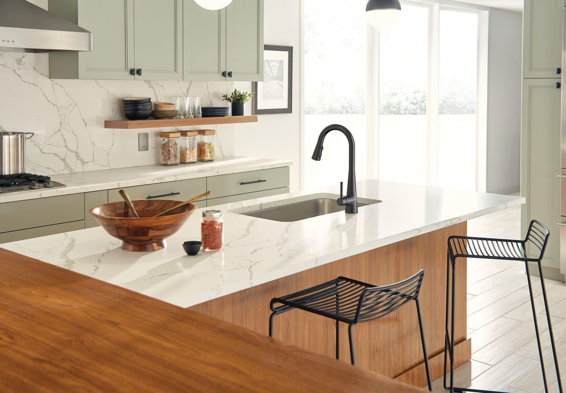 Matte black single-handle kitchen faucet with pulldown sprayer installed over stainless steel sink in marble countertop.