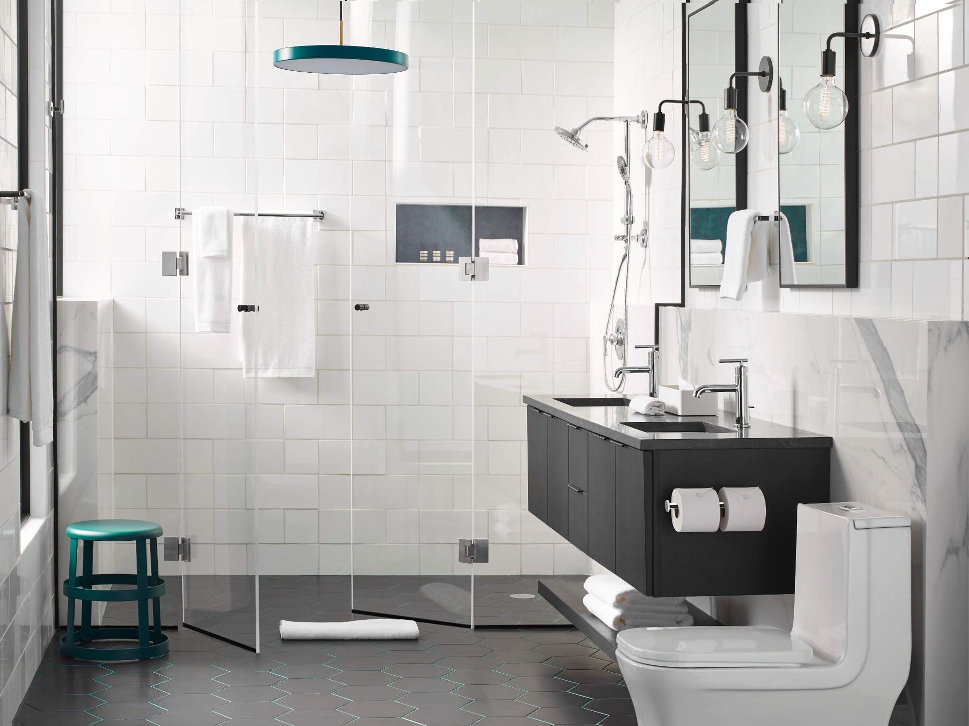 Chrome double post toilet paper holder mounted on black vanity cabinet in bathroom.