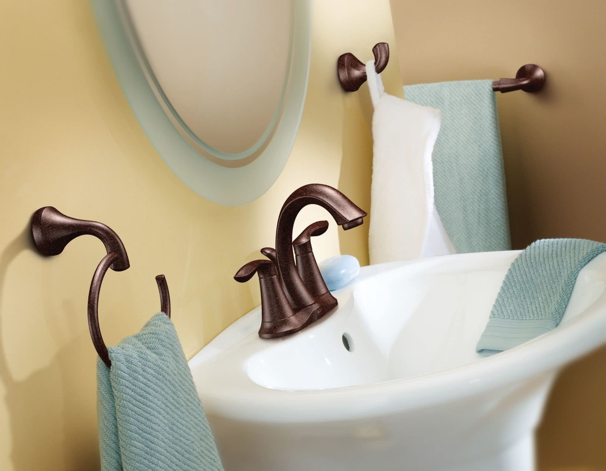 Oil rubbed bronze towel ring mounted on bathroom wall above sink with white and light blue towels.