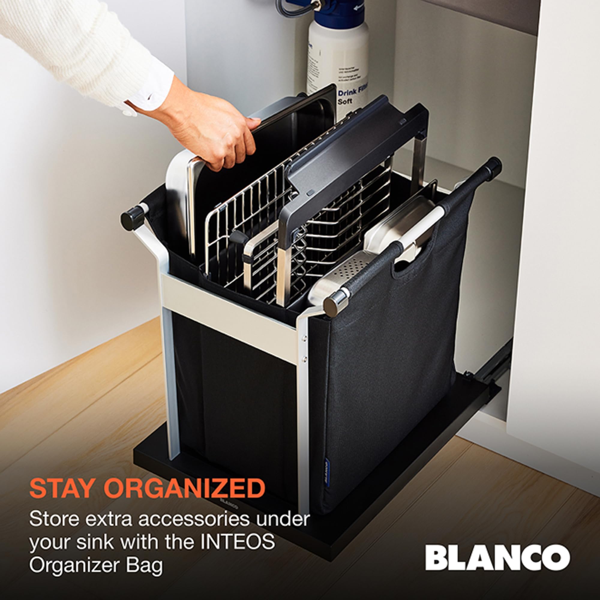 Black sink organizer with removable dividers and compartments, shown installed under a sink with a hand pulling out the top t