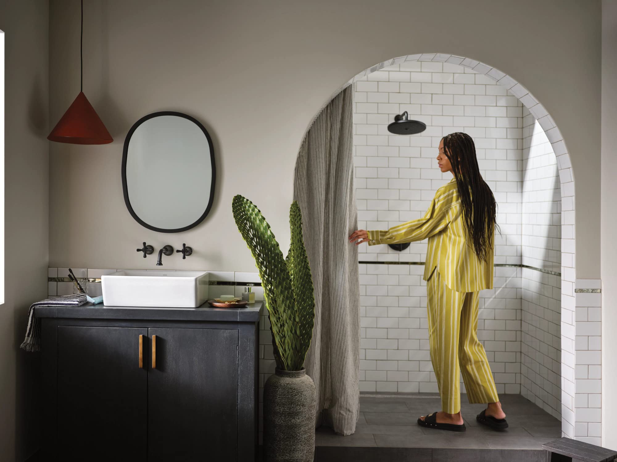 Matte black single-handle shower trim kit mounted on white subway tile wall with overhead rainfall showerhead.