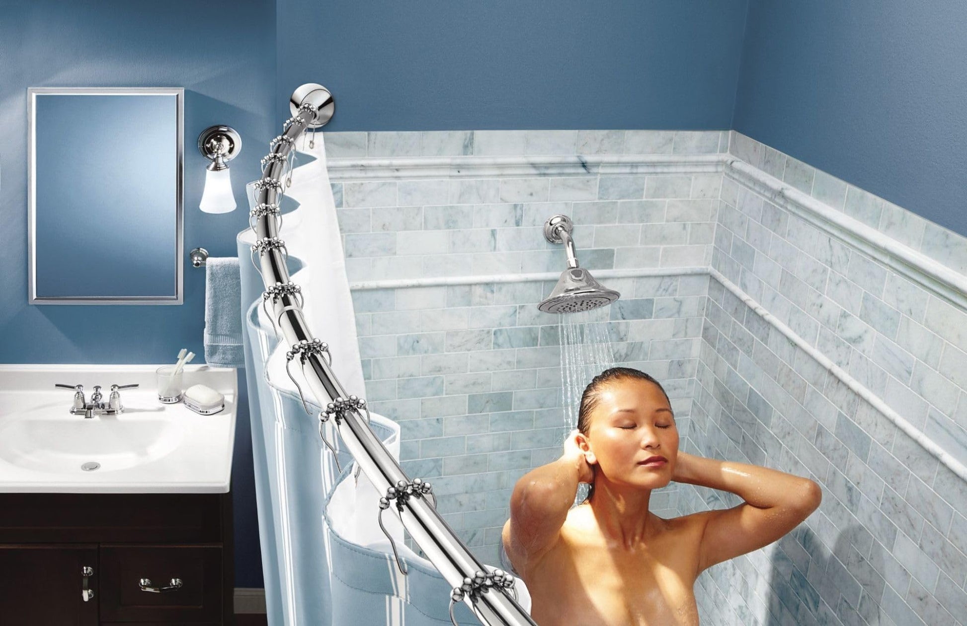 Chrome curved tension shower rod with white shower curtain installed in bathroom with marble tile surround.