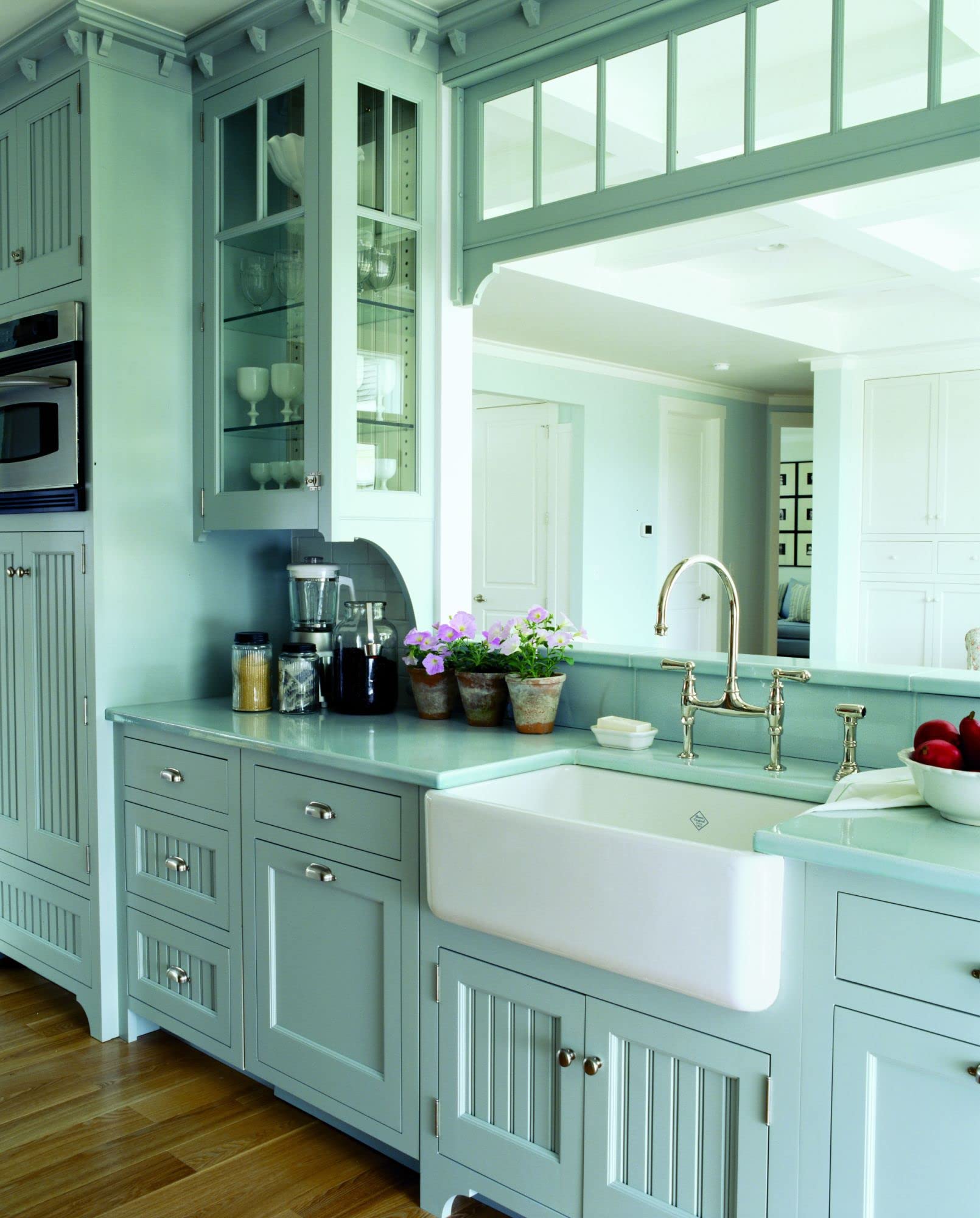 Satin English gold bridge kitchen faucet with curved spout and side spray mounted on white farmhouse sink.