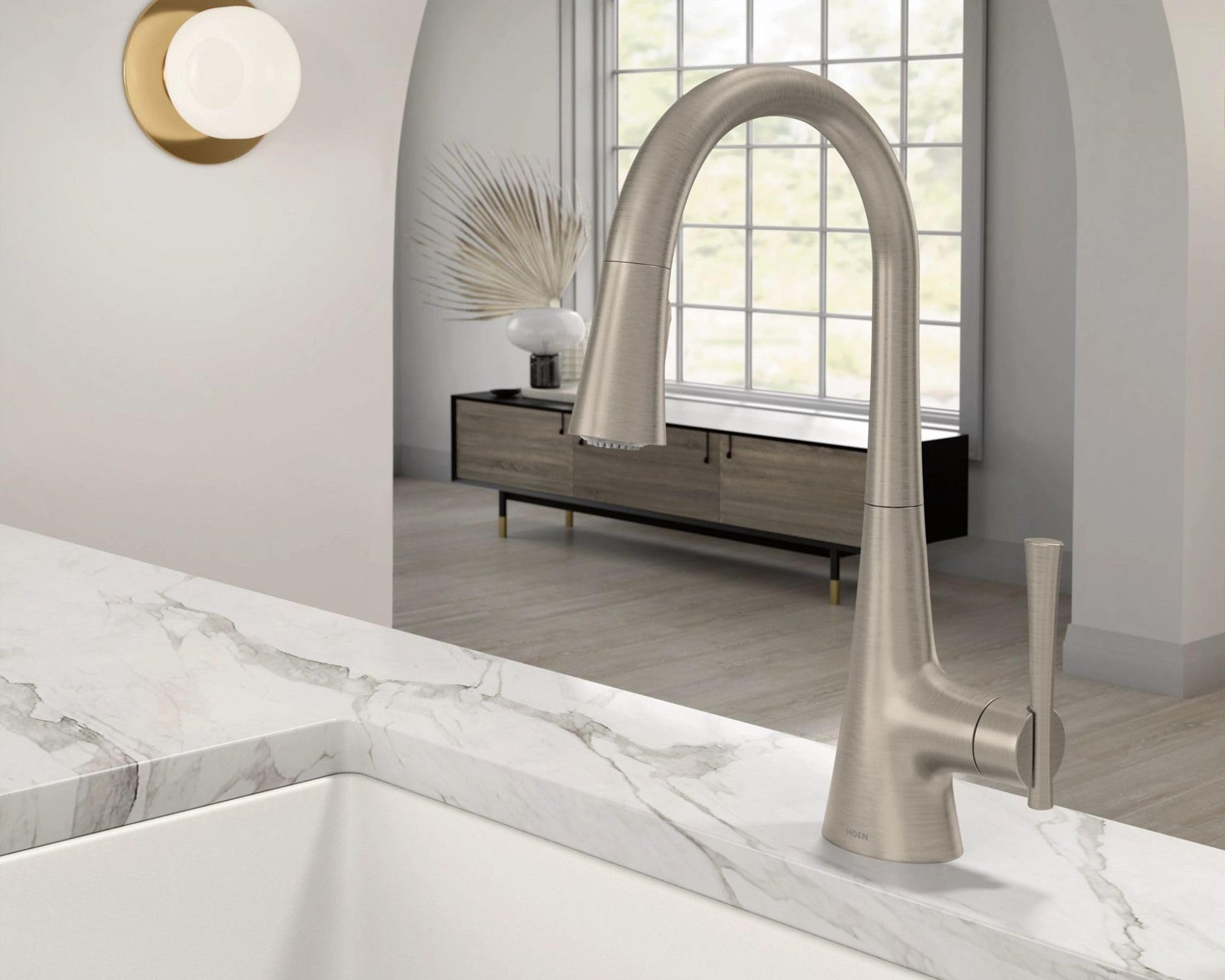Stainless steel pulldown kitchen faucet with curved spout and single handle mounted on marble countertop.