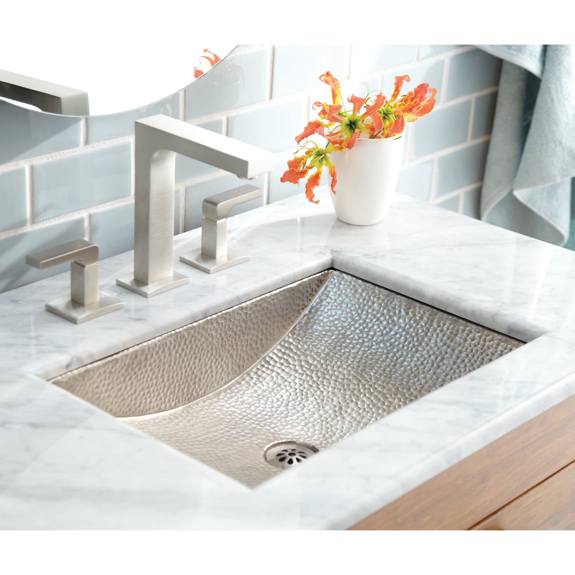 Polished copper undermount sink with hammered interior finish installed in marble countertop with matching faucet.