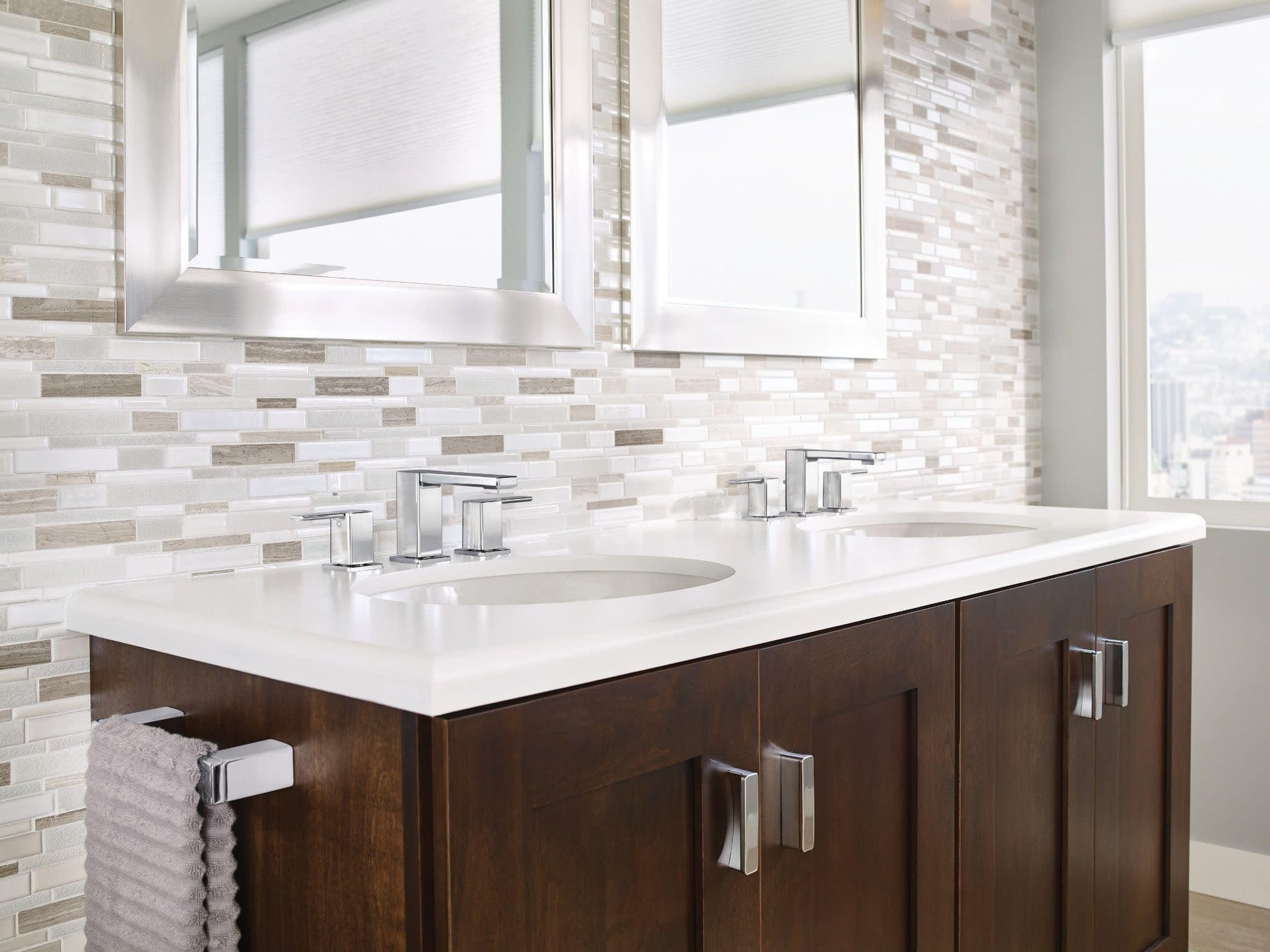 Chrome two-handle widespread bathroom faucet with angular spout installed on white countertop.