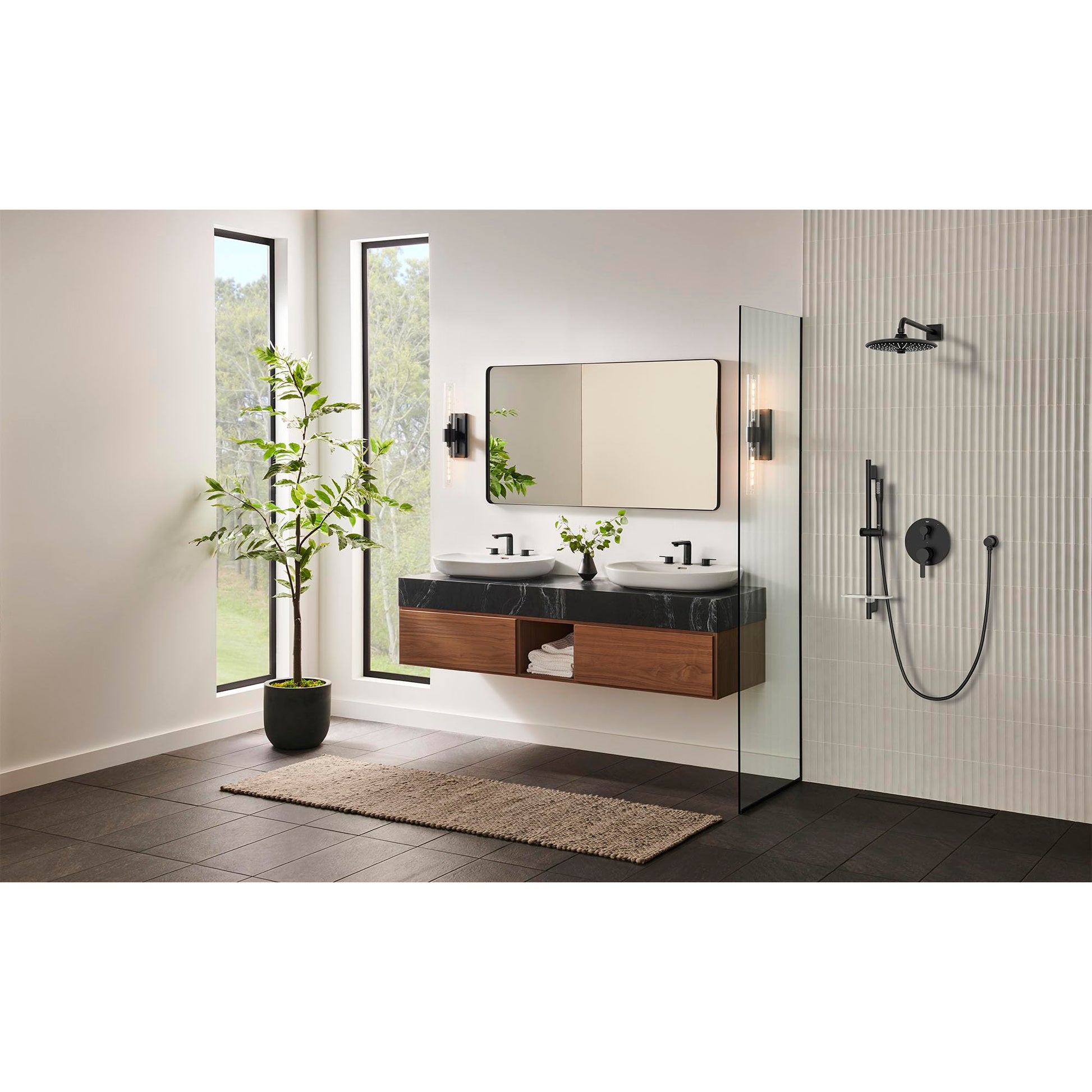 Matte black shower valve trim with diverter handle and cartridge mounted on bathroom wall beside glass enclosure.
