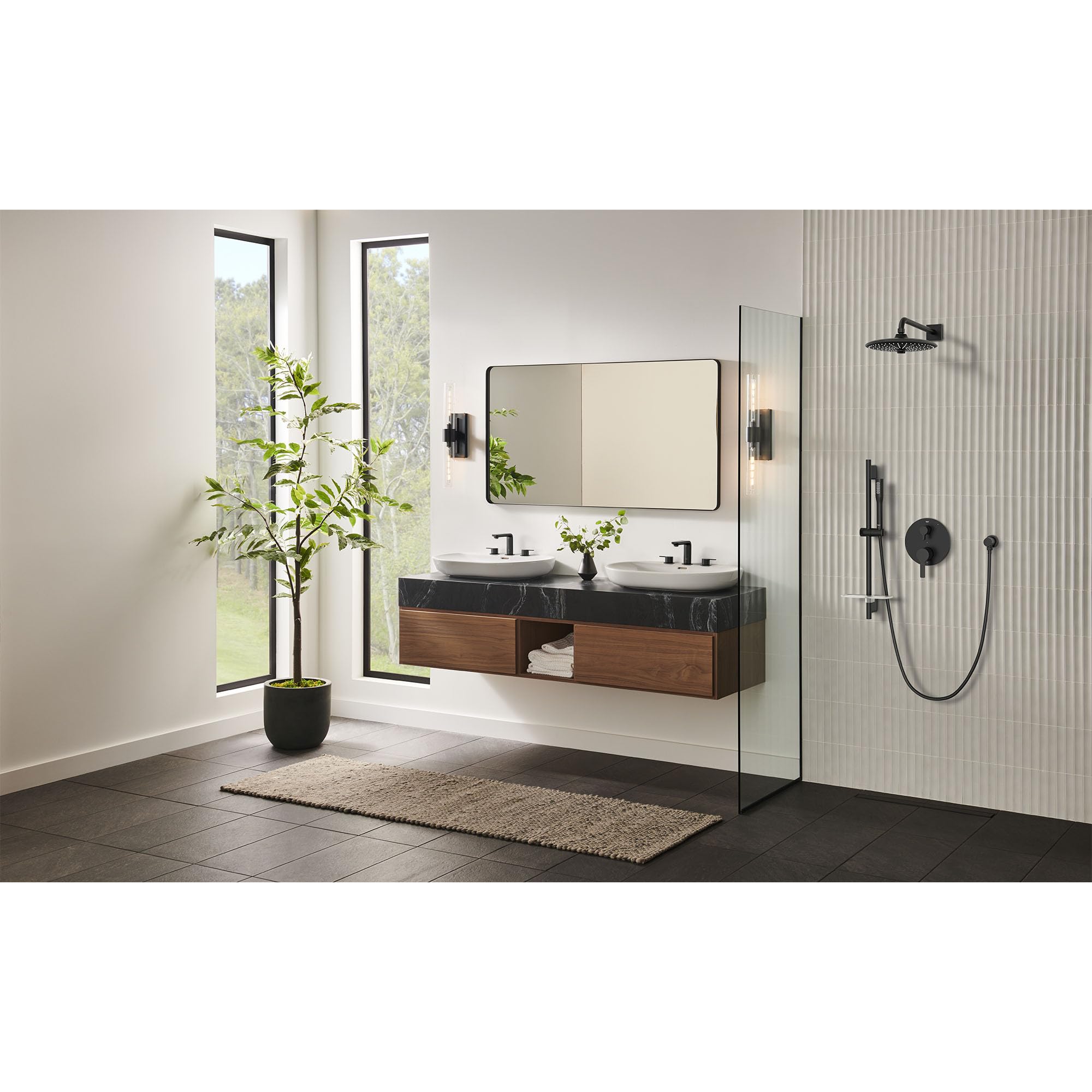 Matte black shower valve trim with diverter handle and cartridge mounted on bathroom wall beside glass enclosure.