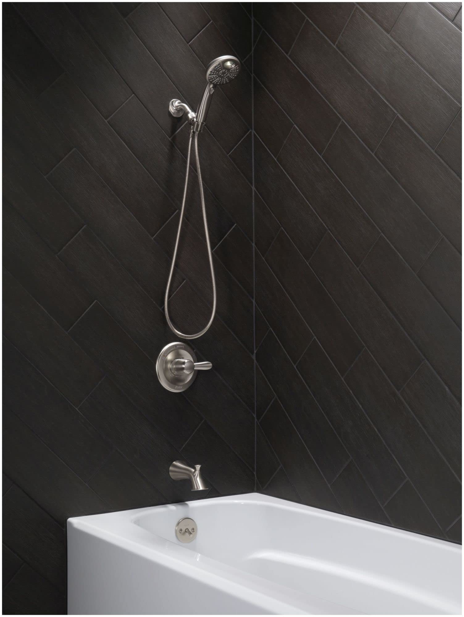Black stainless steel shower valve trim with handheld showerhead, spout, and control lever installed on dark tile wall above 