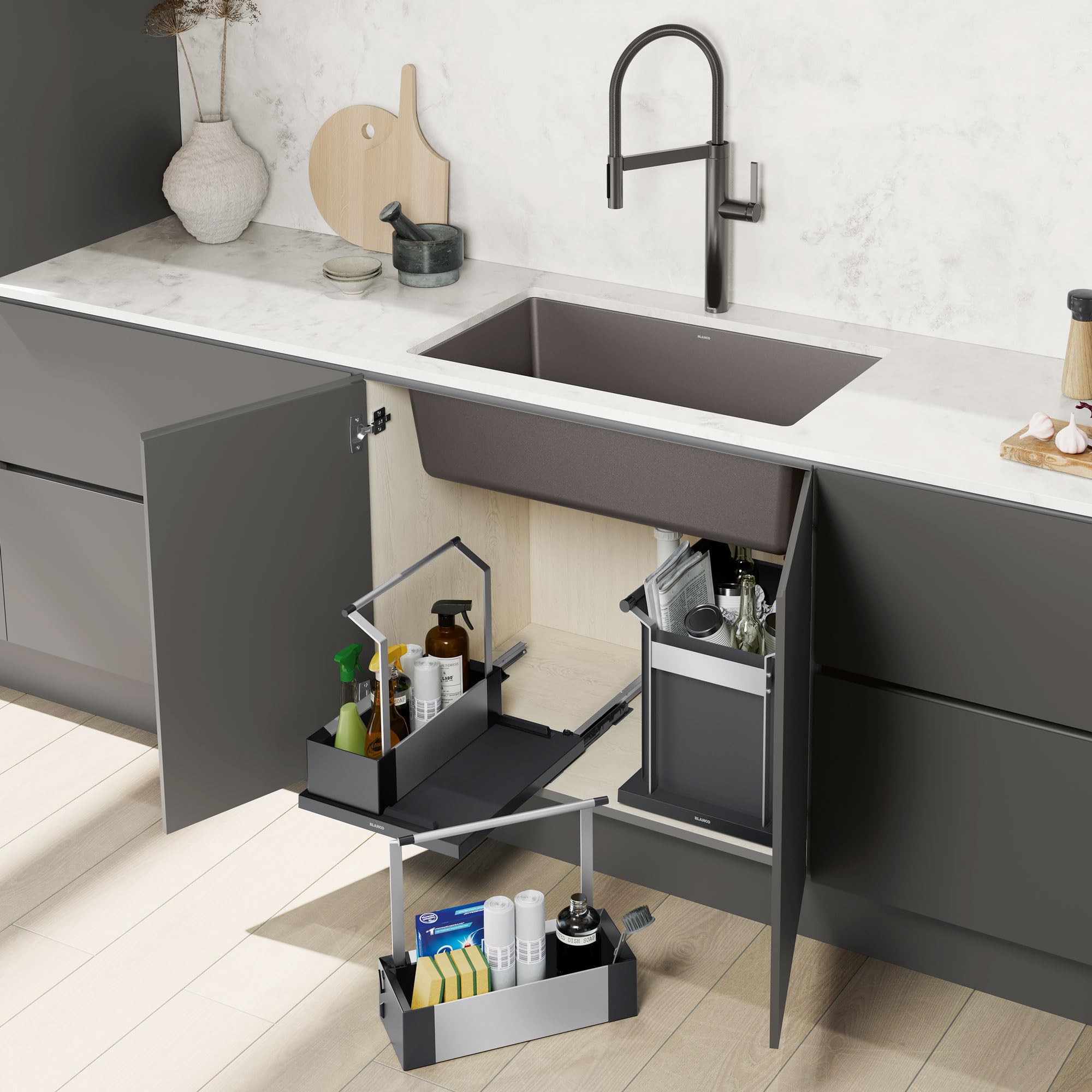 Two-tier black storage caddy with pull-out baskets positioned under kitchen sink, containing bottles and cleaning supplies.