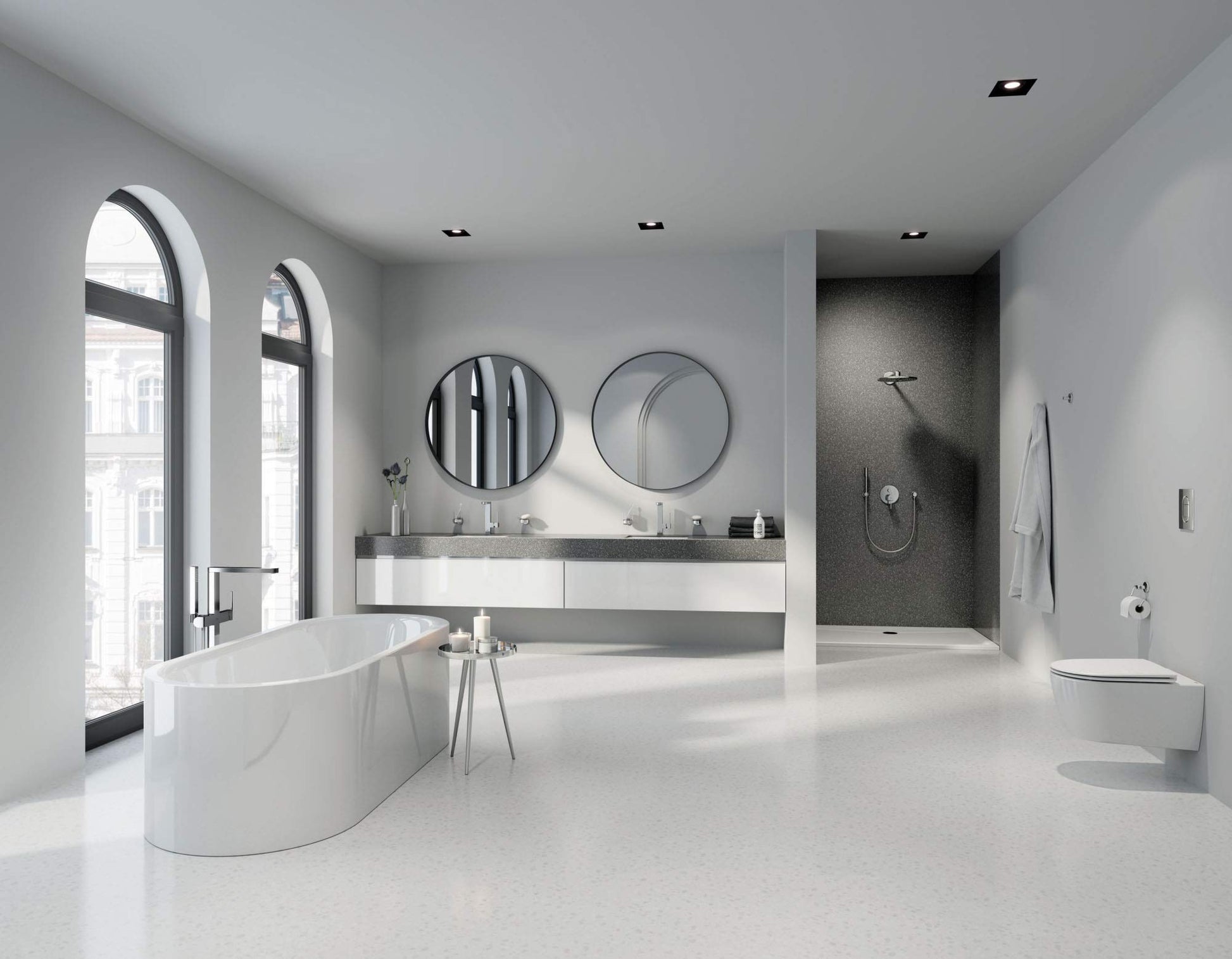 Chrome freestanding tub faucet with single handle and hand shower mounted on white oval bathtub in modern bathroom.