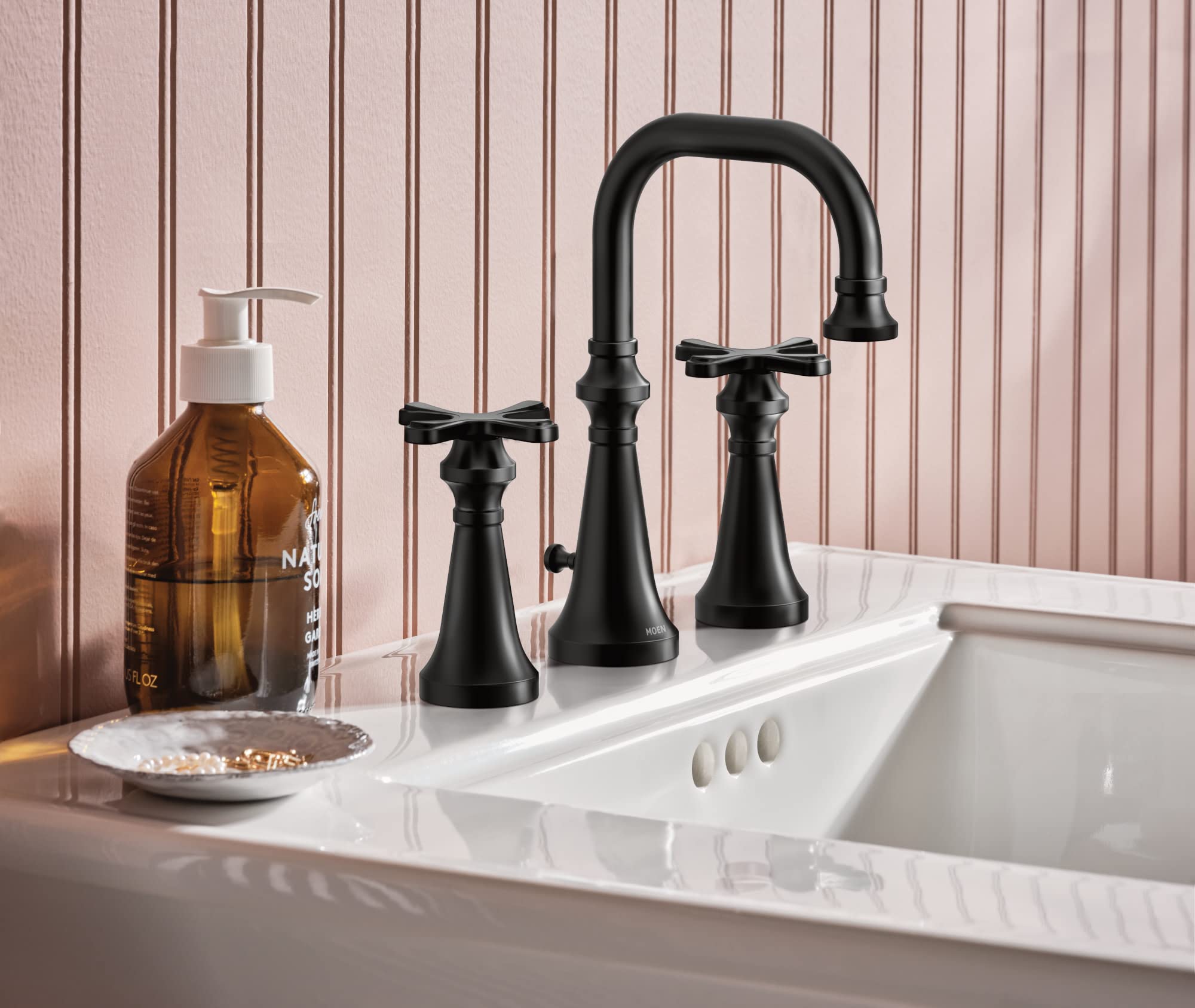 Matte black two-handle bathroom faucet with high arc spout and cross handles installed on white sink.