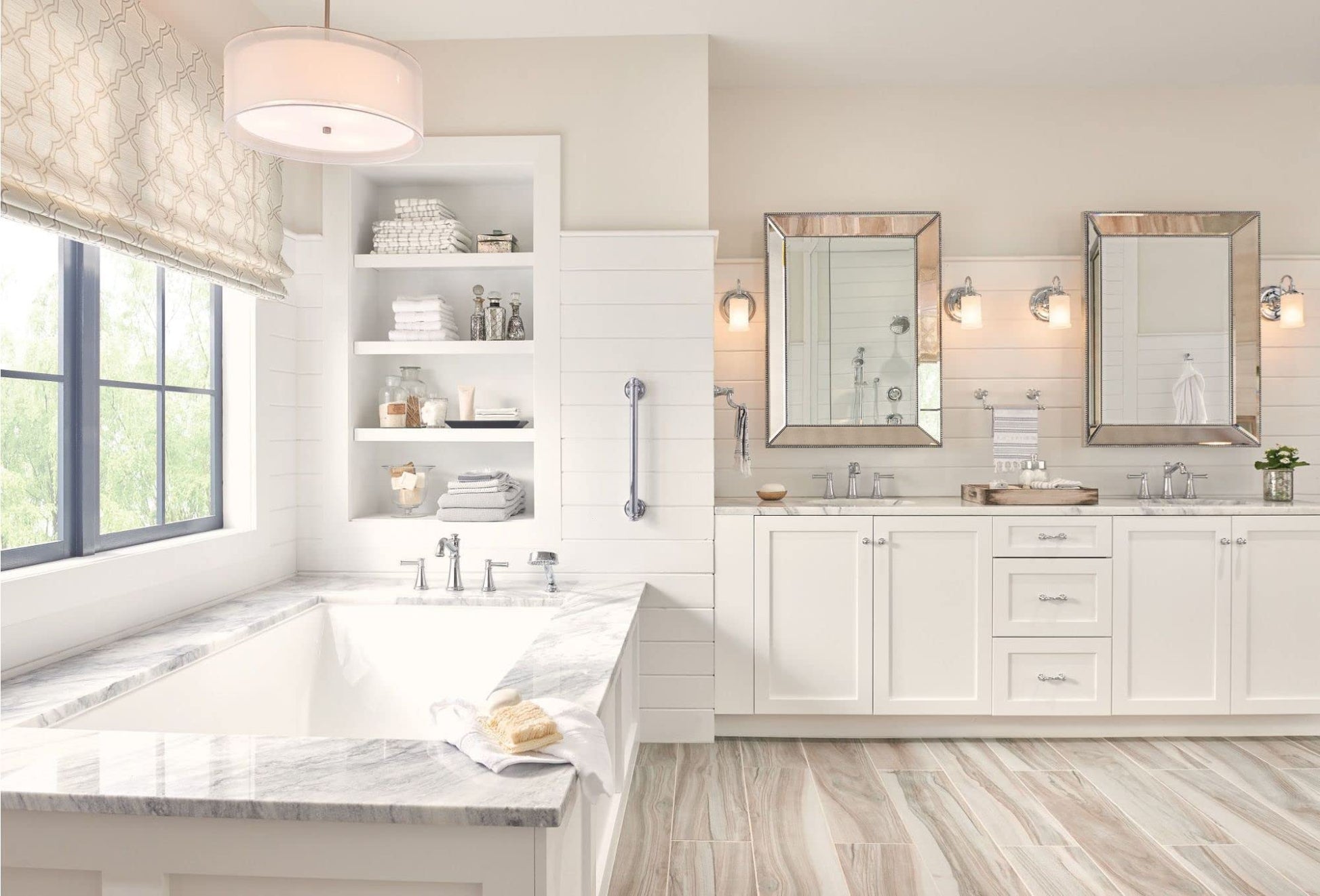 Chrome two-handle deck-mounted Roman tub faucet with hand shower attachment displayed in bathroom setting.