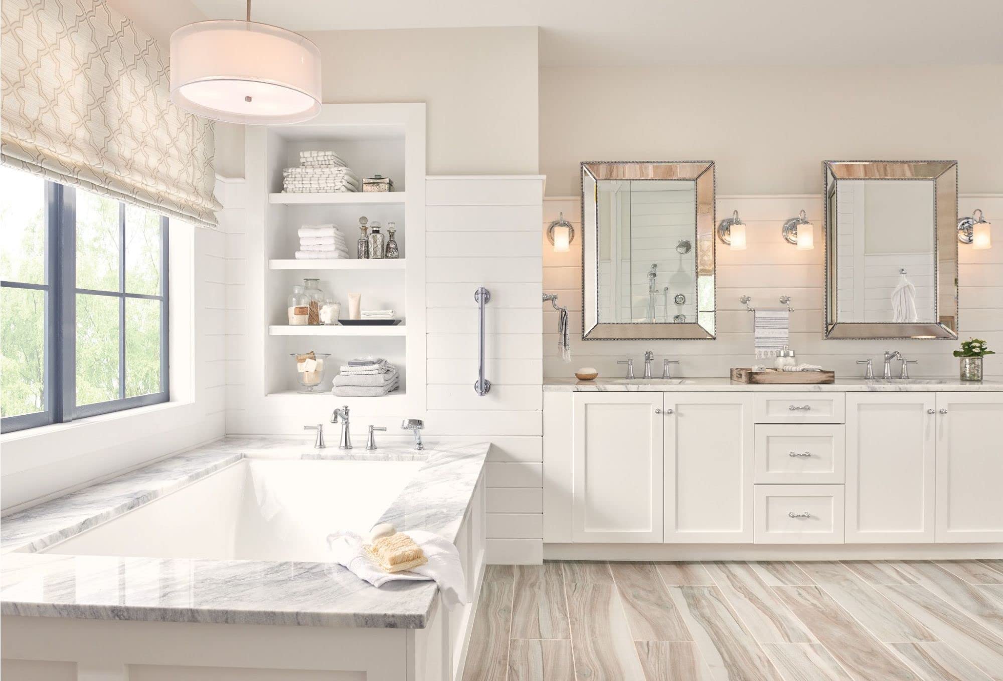 Chrome two-handle deck-mounted Roman tub faucet with hand shower attachment displayed in bathroom setting.