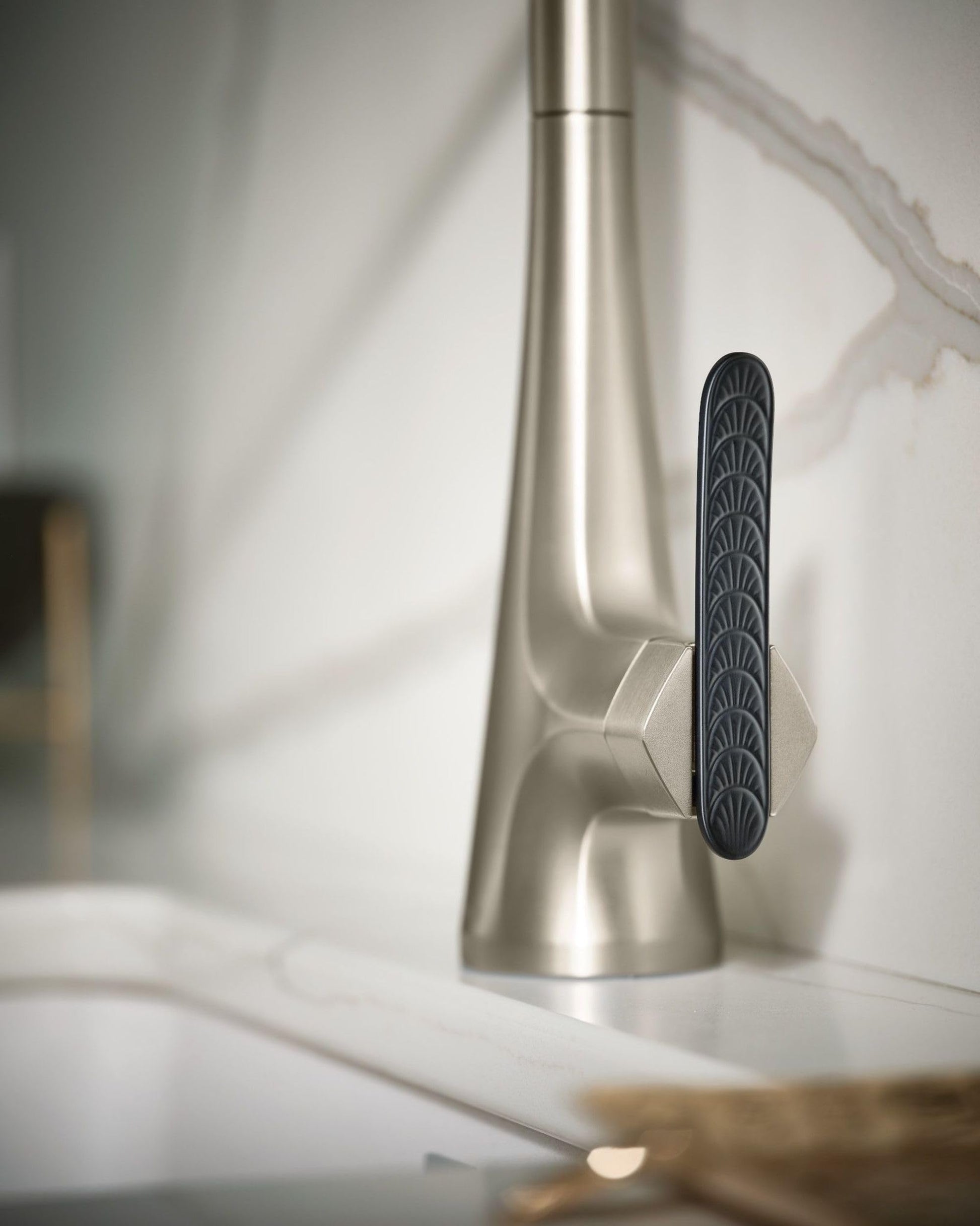 Stainless steel pulldown kitchen faucet with high arc spout and black handle lever on white sink counter.