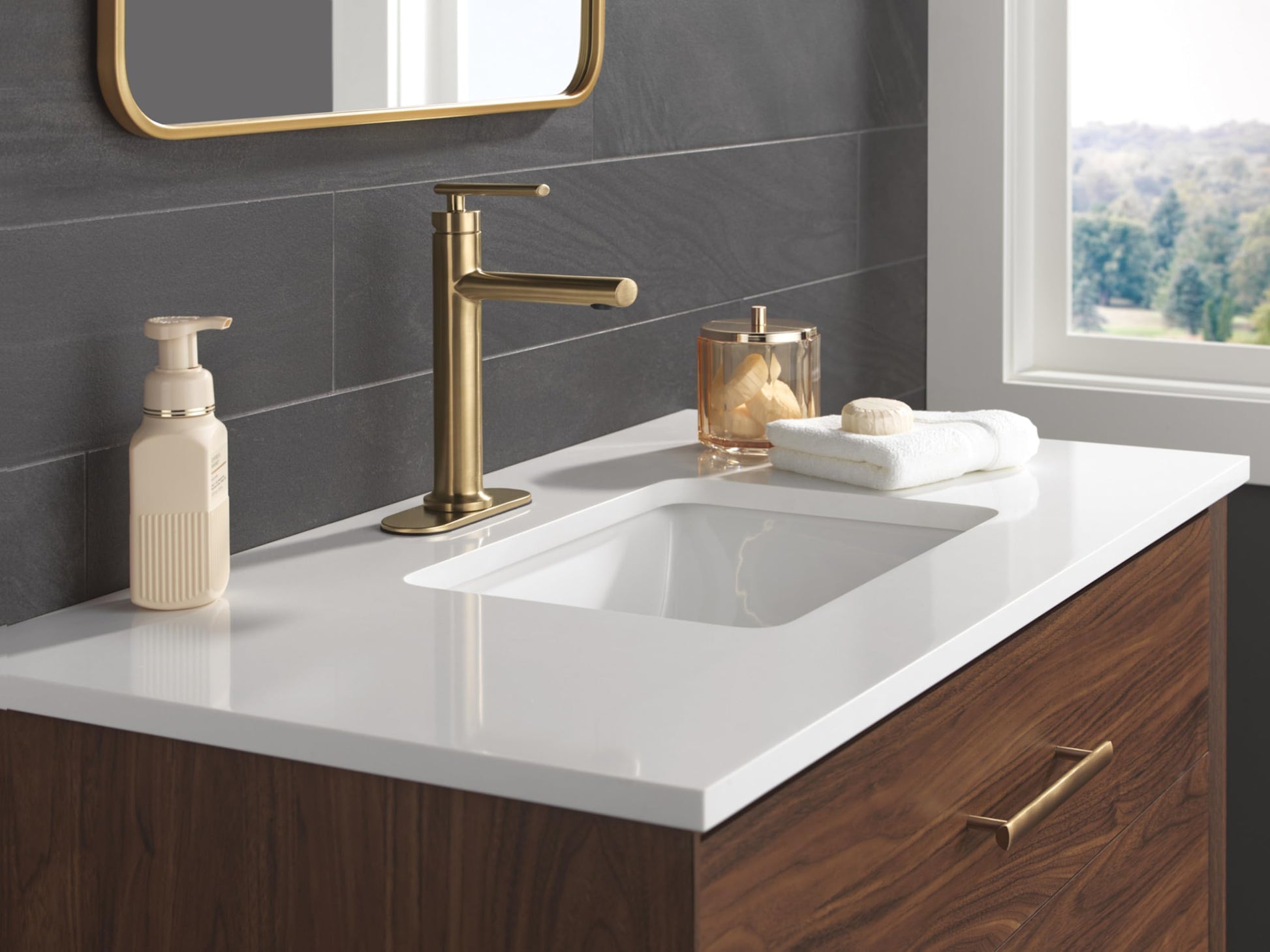 Champagne bronze single-handle bathroom faucet with tall spout installed on white countertop above undermount sink.