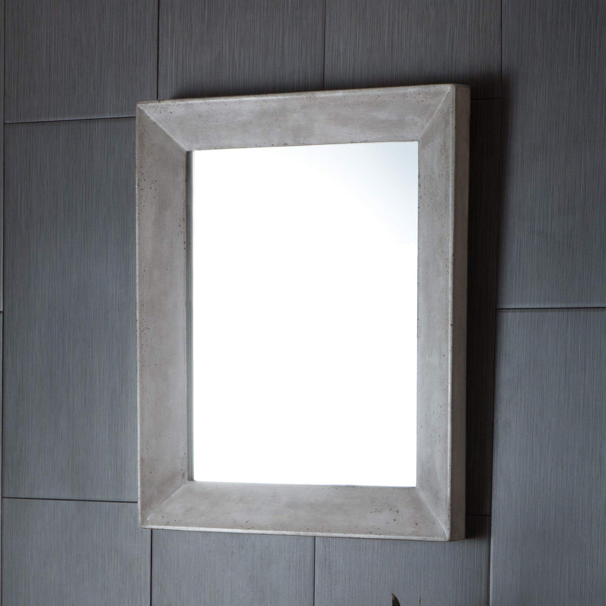 Rectangular wall mirror with ash-colored concrete frame mounted on gray tile wall.