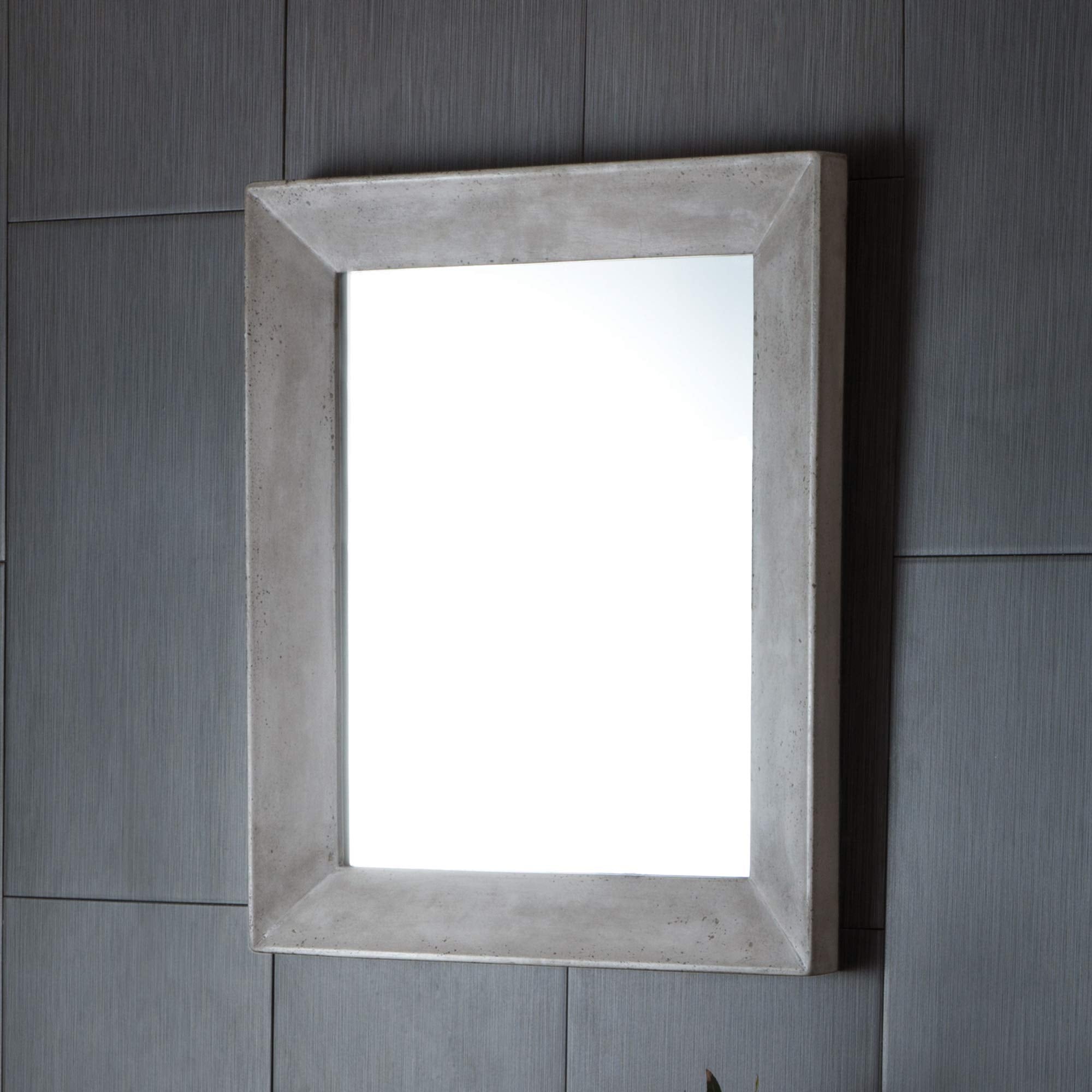 Rectangular wall mirror with ash-colored concrete frame mounted on gray tile wall.