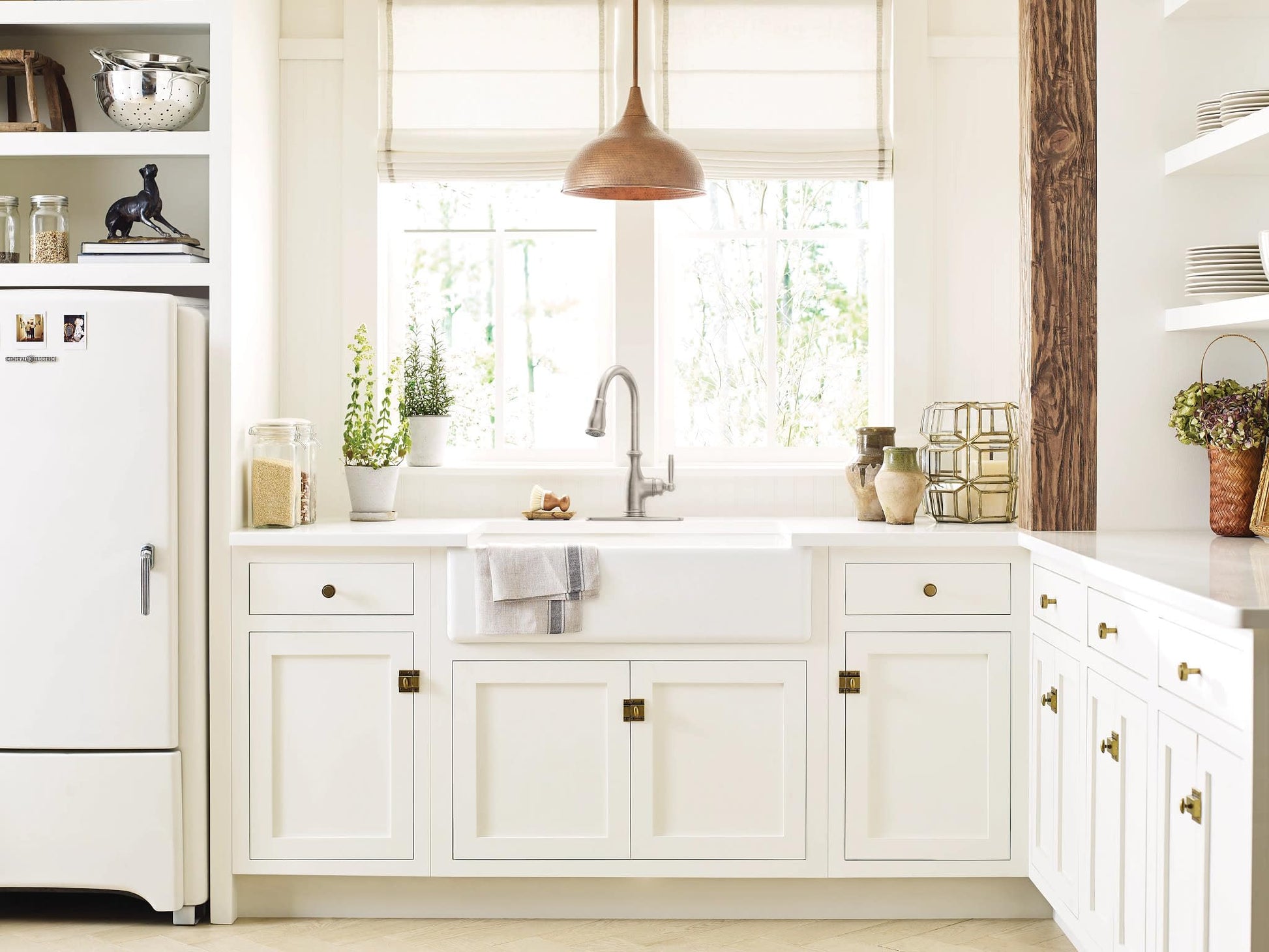 Stainless steel pull-down kitchen faucet with single side handle mounted above white farmhouse sink.