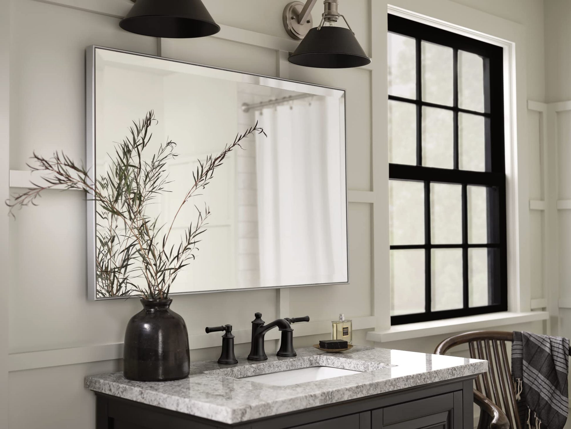 Matte black two-handle high-arc bathroom sink faucet with widespread mounting on marble countertop.