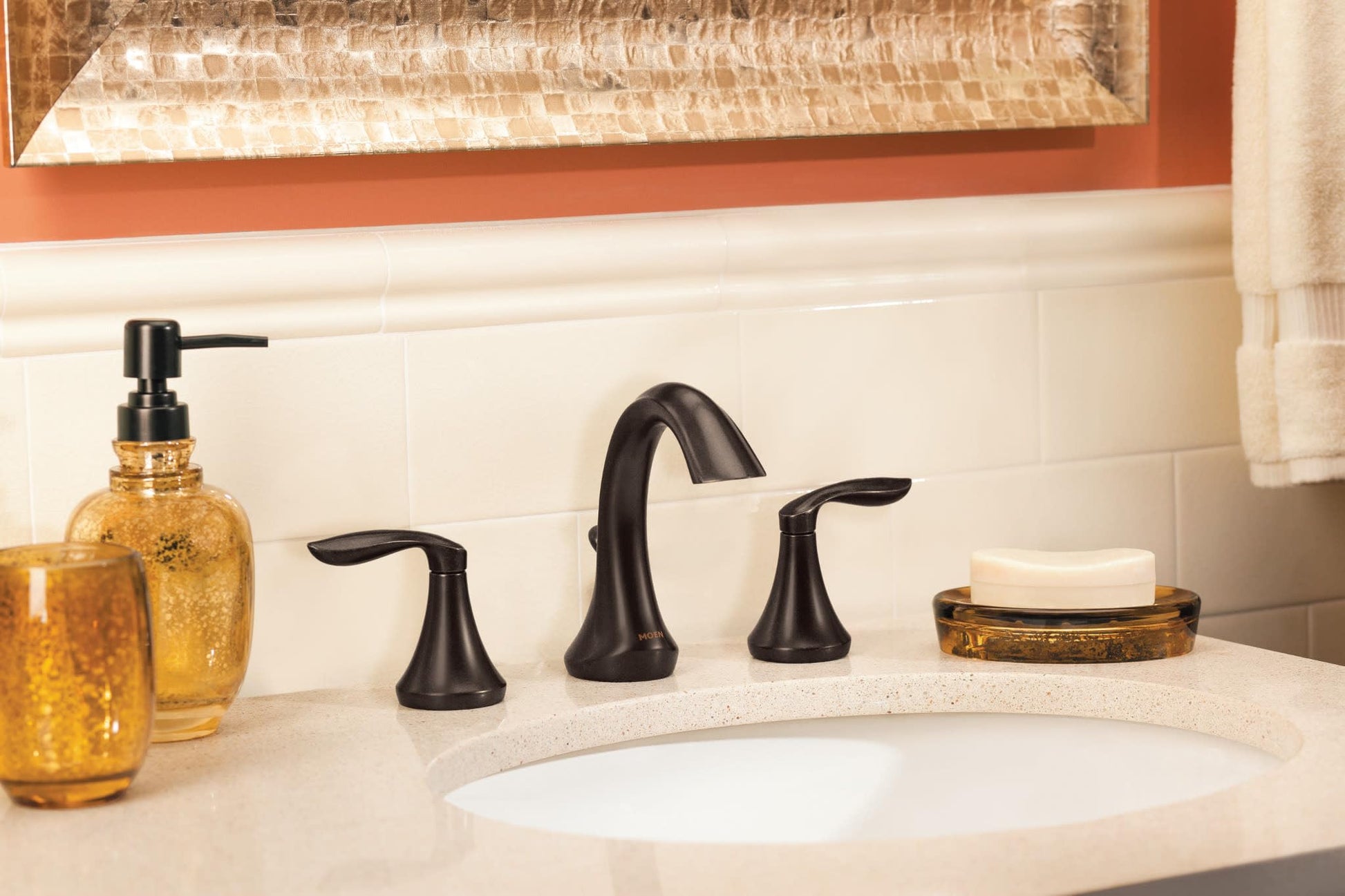 Oil rubbed bronze two-handle bathroom faucet with high arc spout installed on white sink in bathroom vanity.