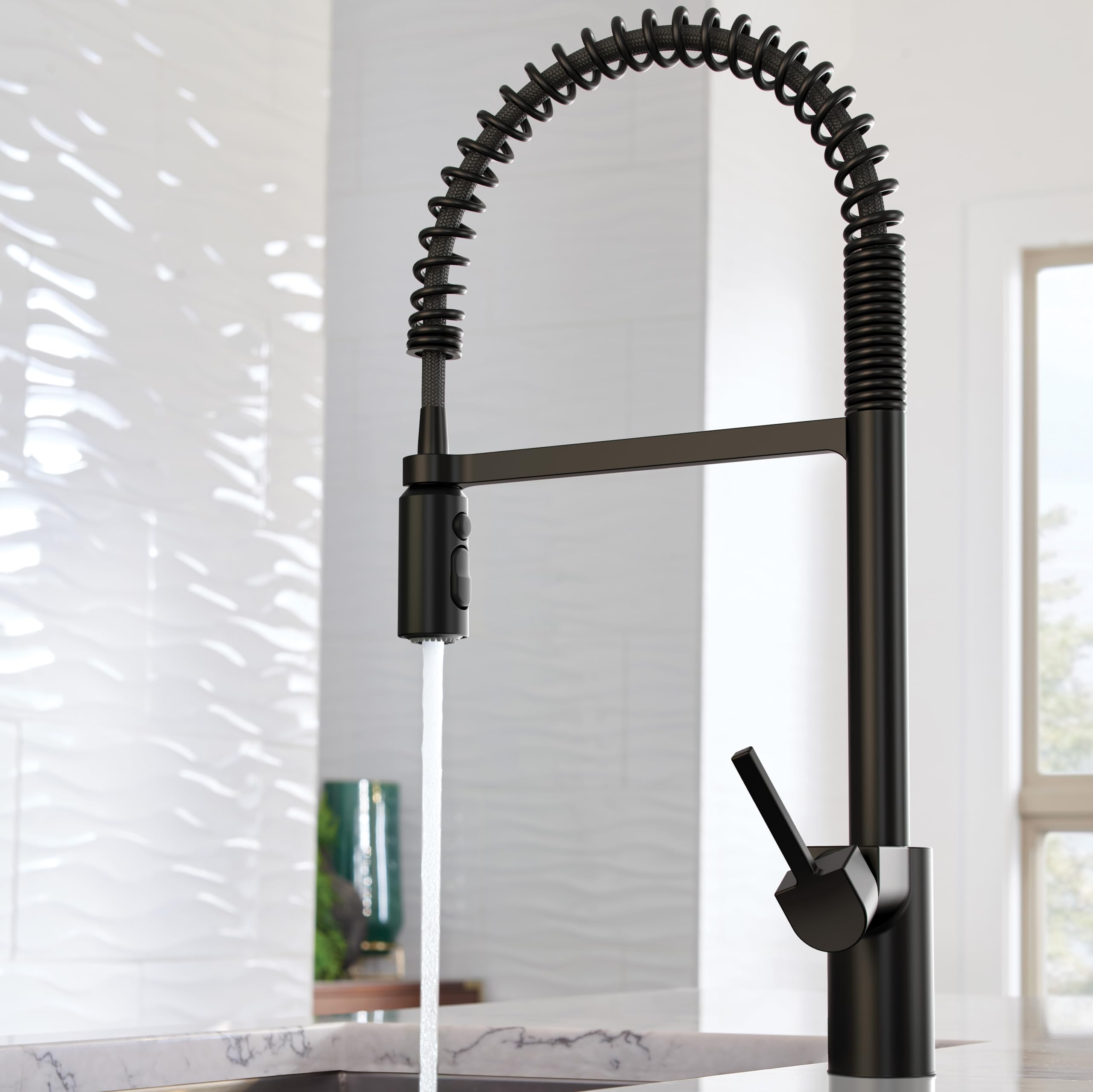 Matte black pre-rinse spring kitchen faucet with coiled hose and single lever handle, water running from spout.