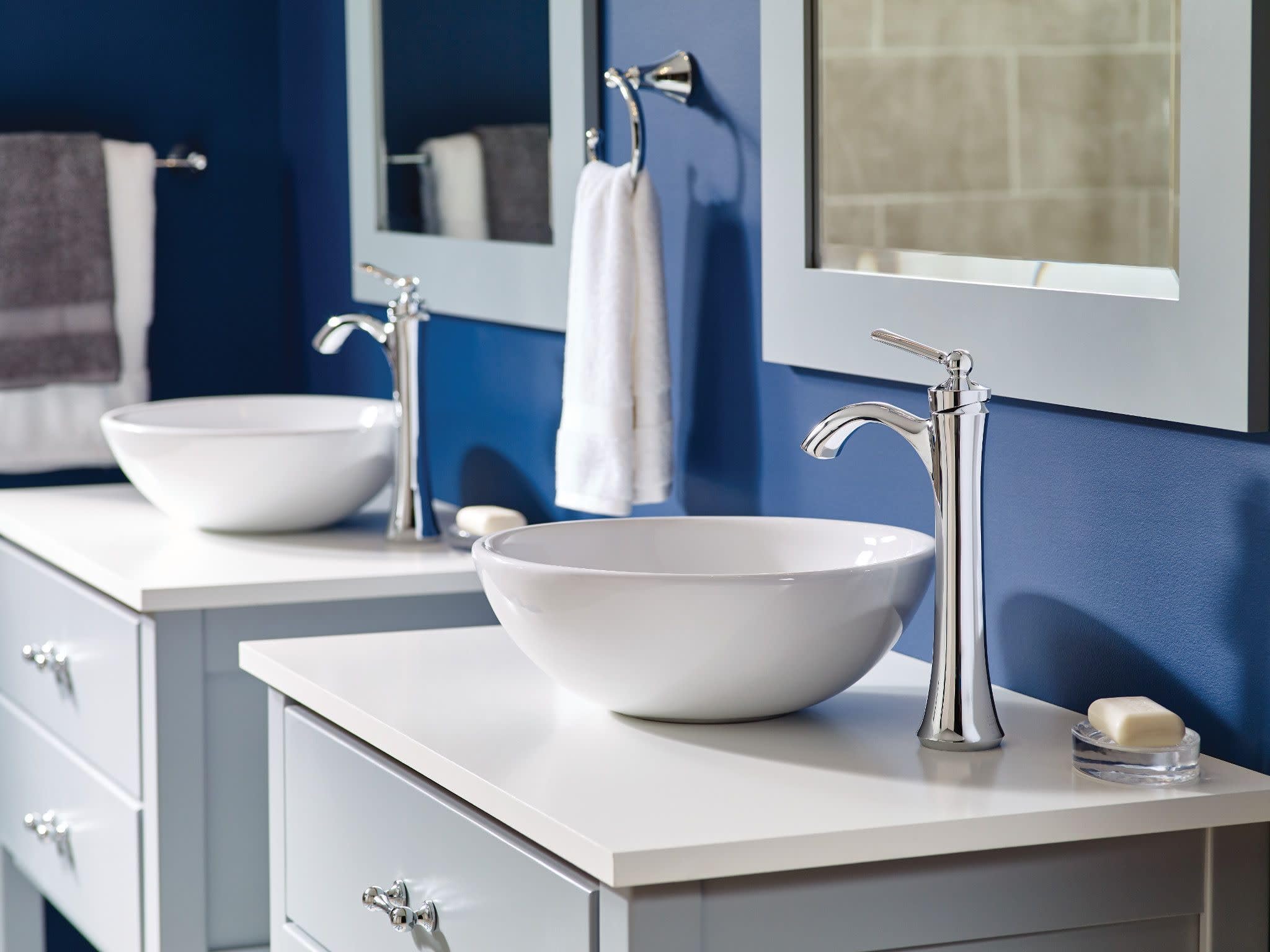 Brushed nickel single-handle high arc faucet with curved spout installed above white vessel sink on bathroom counter.