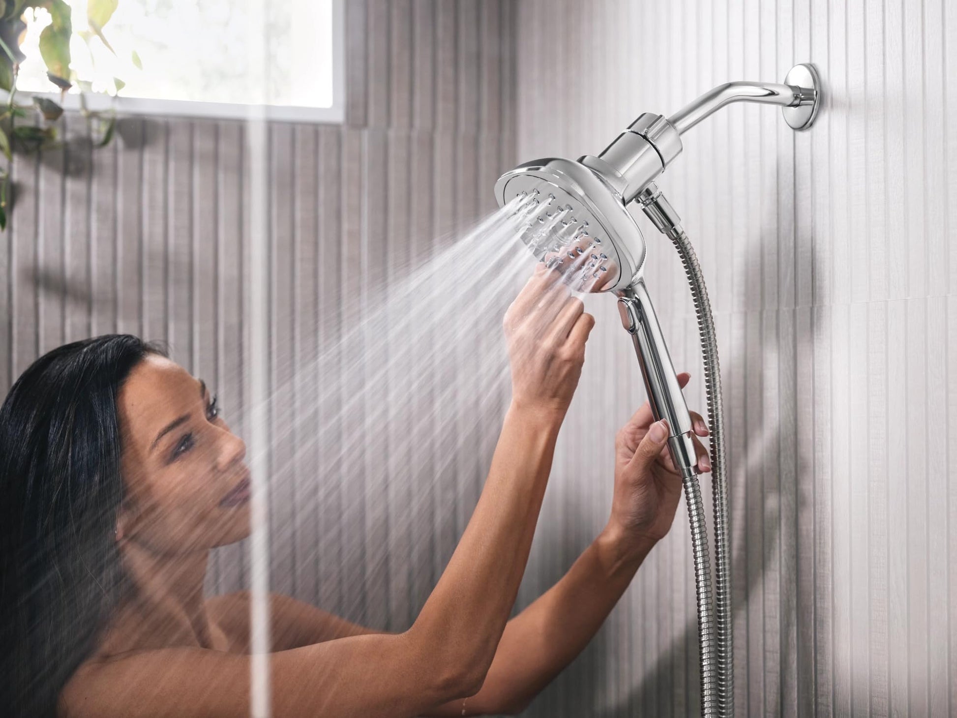 Chrome square handheld shower head with 5-inch diameter spray face mounted on wall with hose attachment.