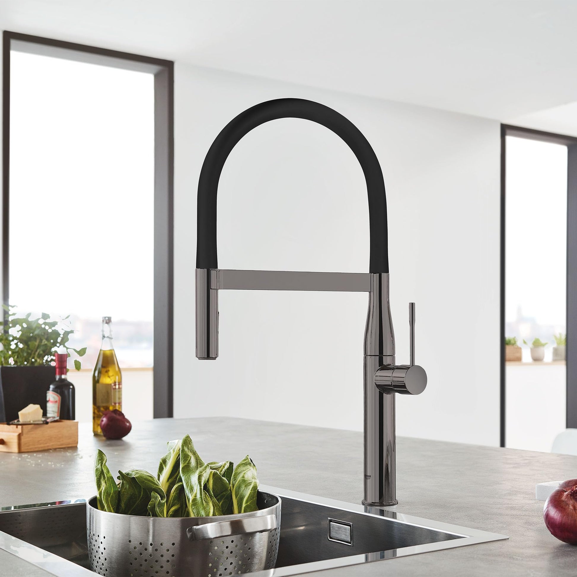 Dark graphite single-handle kitchen faucet with high arched spout and black pull-down spray head over sink.