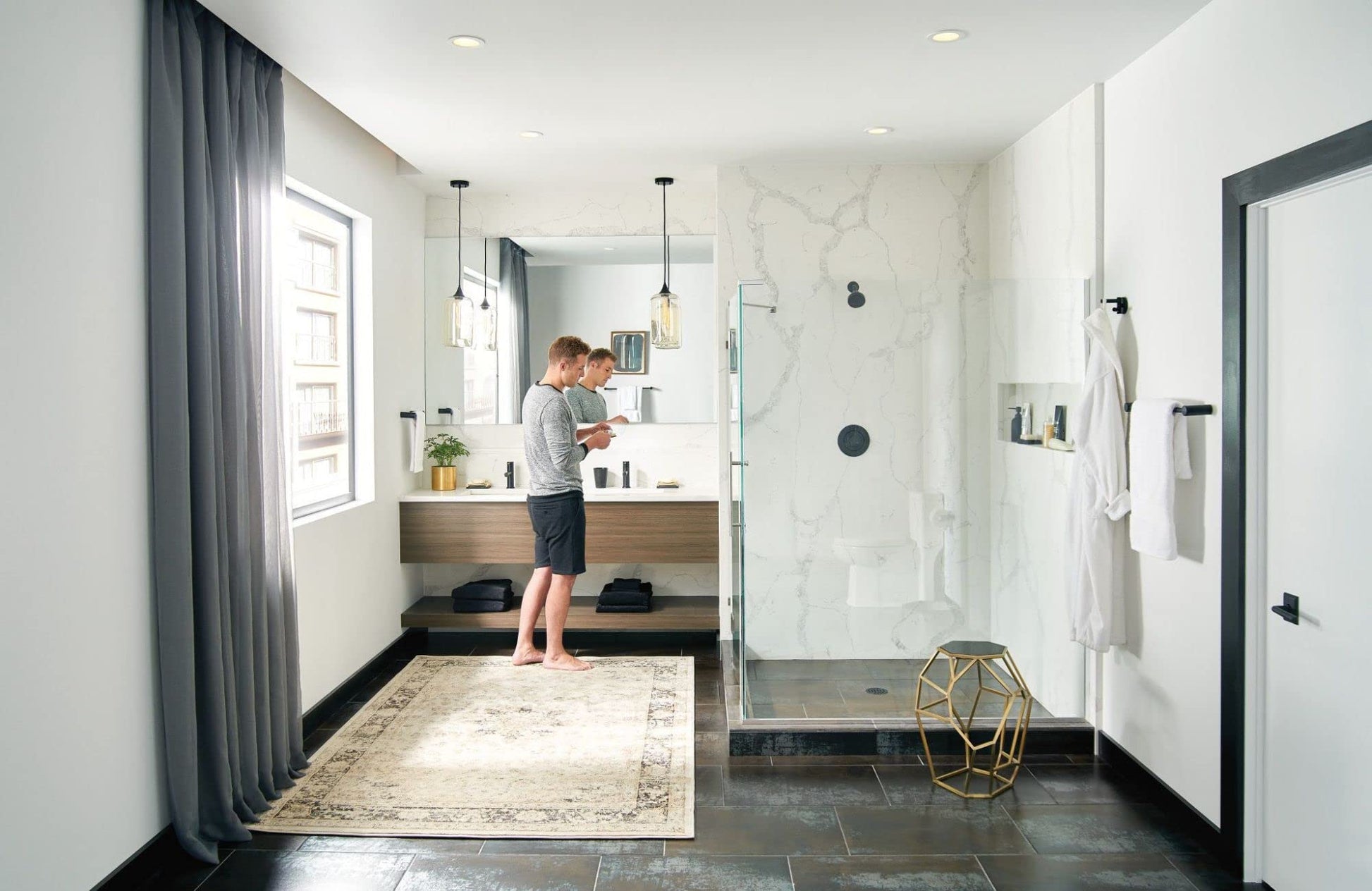 Matte black fixed showerhead mounted on white marble shower wall in bathroom setting.