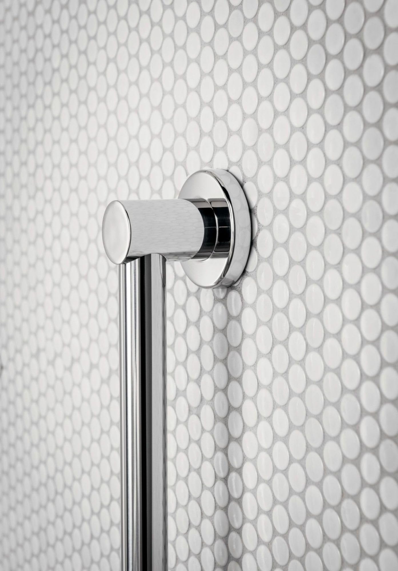 Chrome grab bar mounted vertically on white penny tile wall with round mounting flange and cylindrical handle.