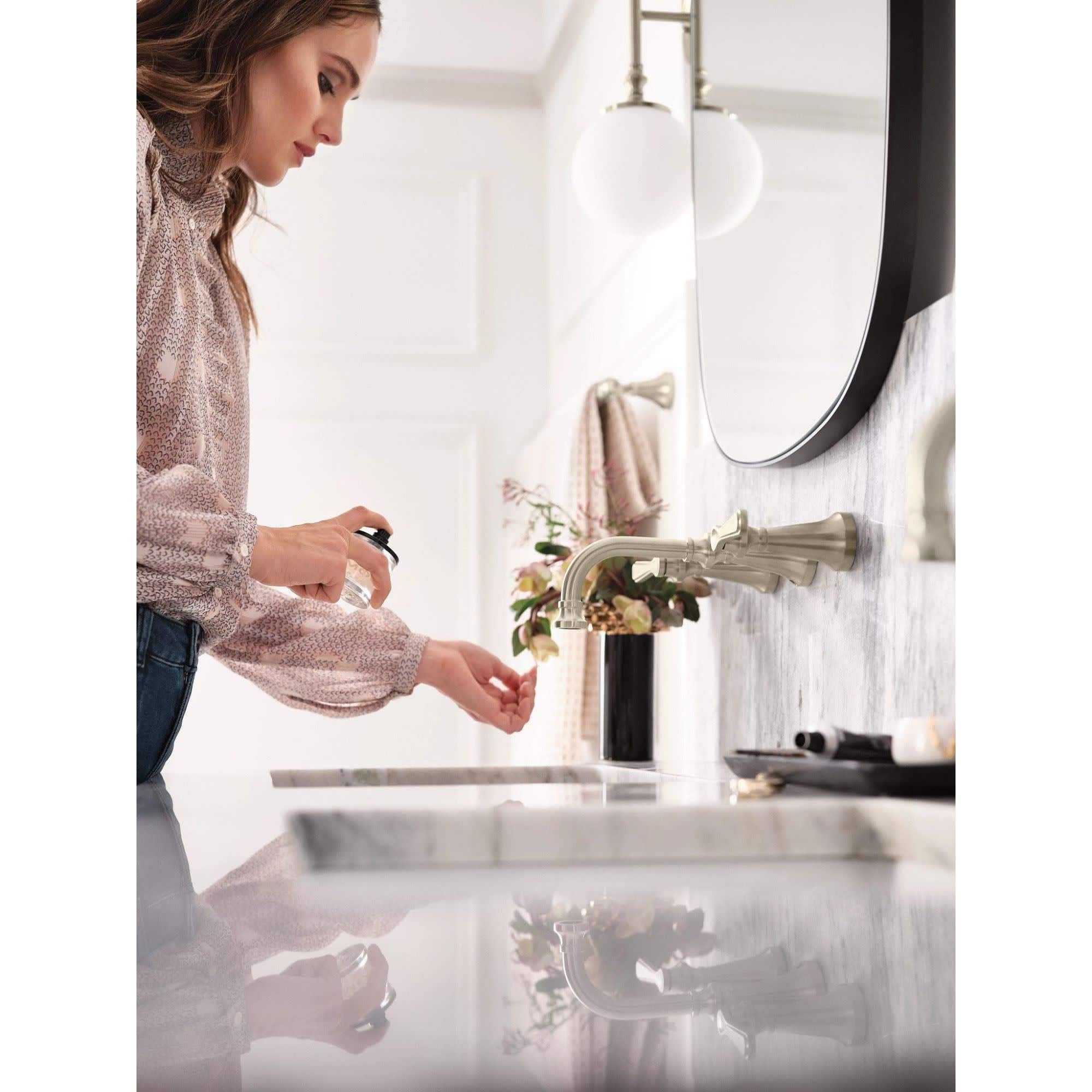 Matte black wall-mounted bathroom faucet with traditional lever handle installed above white sink.