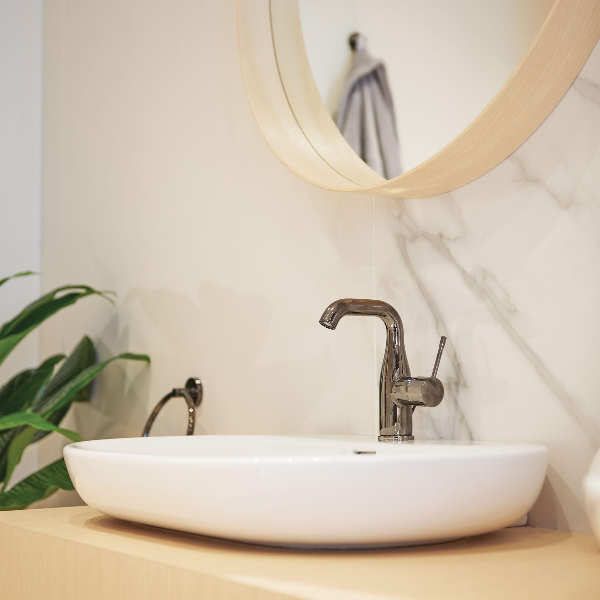 Dark gray single-handle bathroom faucet with curved spout mounted on white vessel sink.