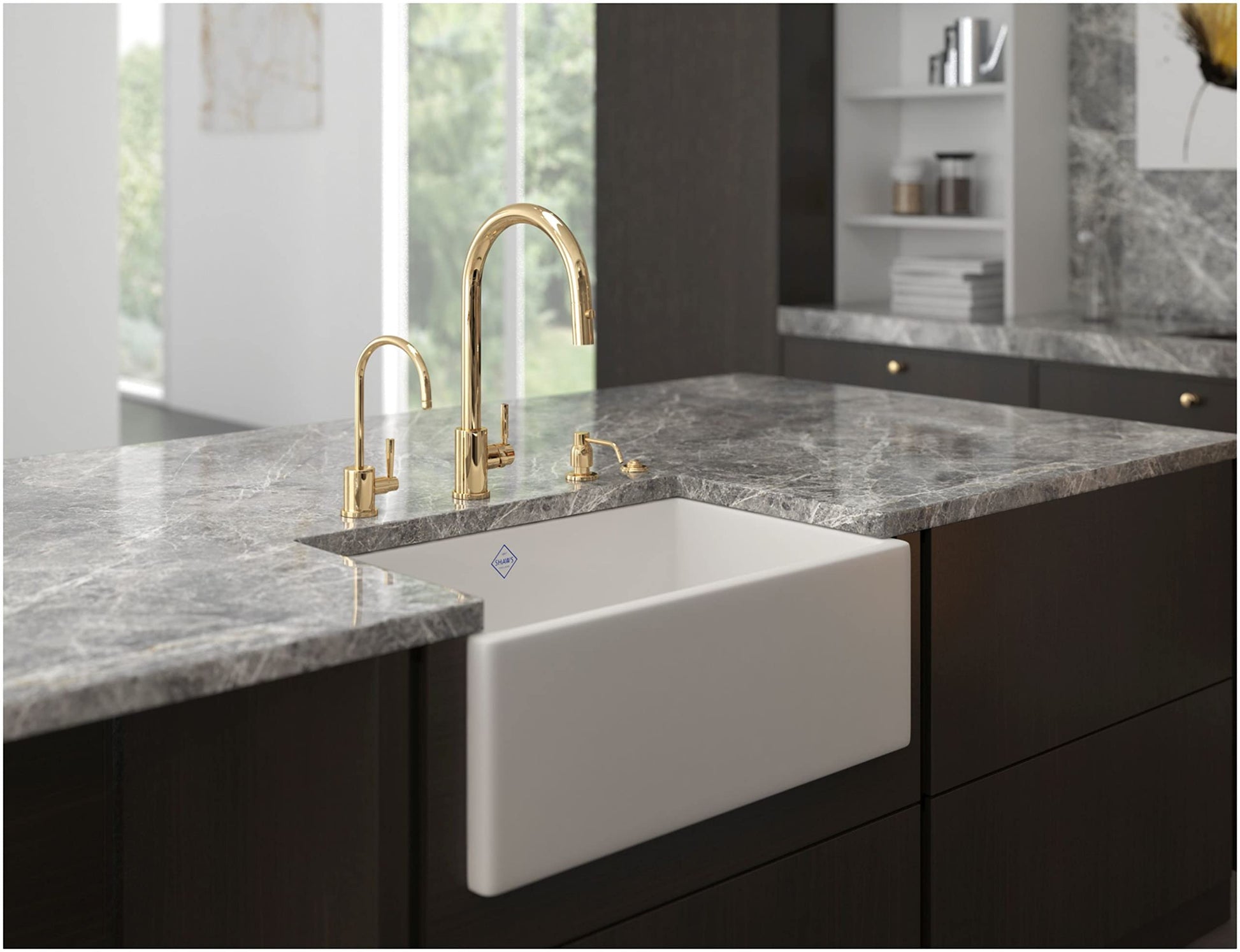 Satin English gold kitchen faucet with curved spout mounted above white apron-front sink in gray countertop.