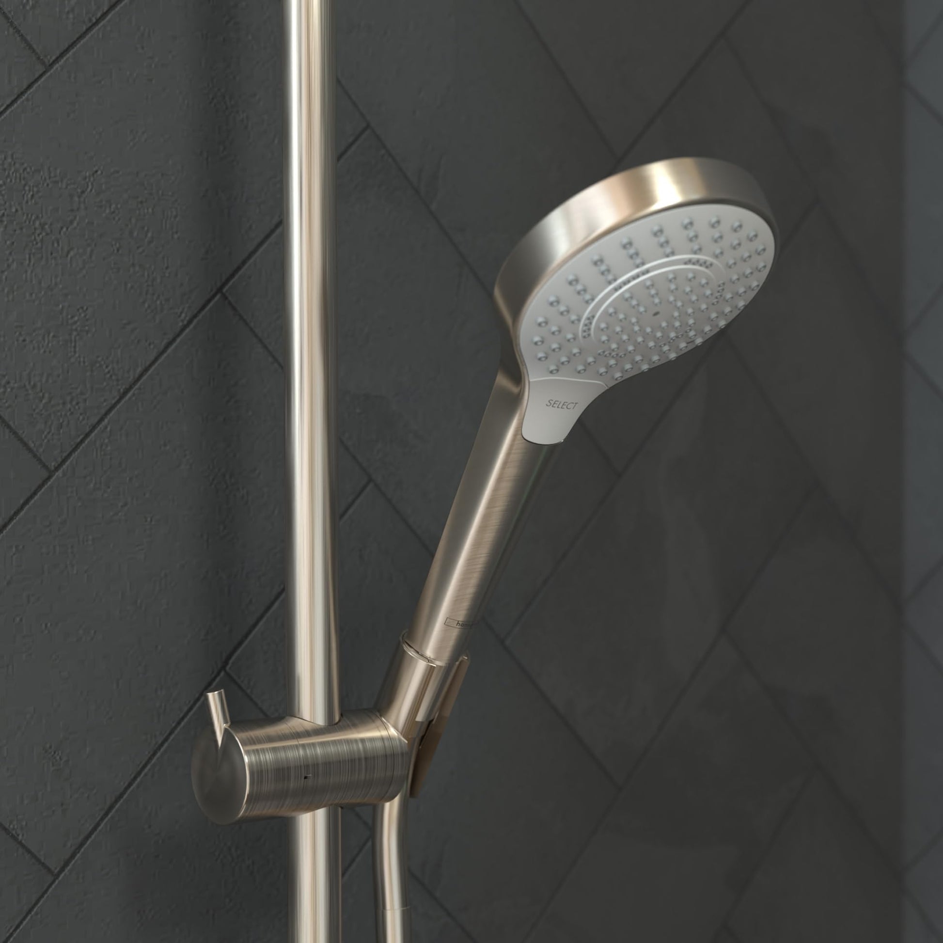 Brushed nickel handshower with round perforated head mounted on vertical rail against dark tile wall.