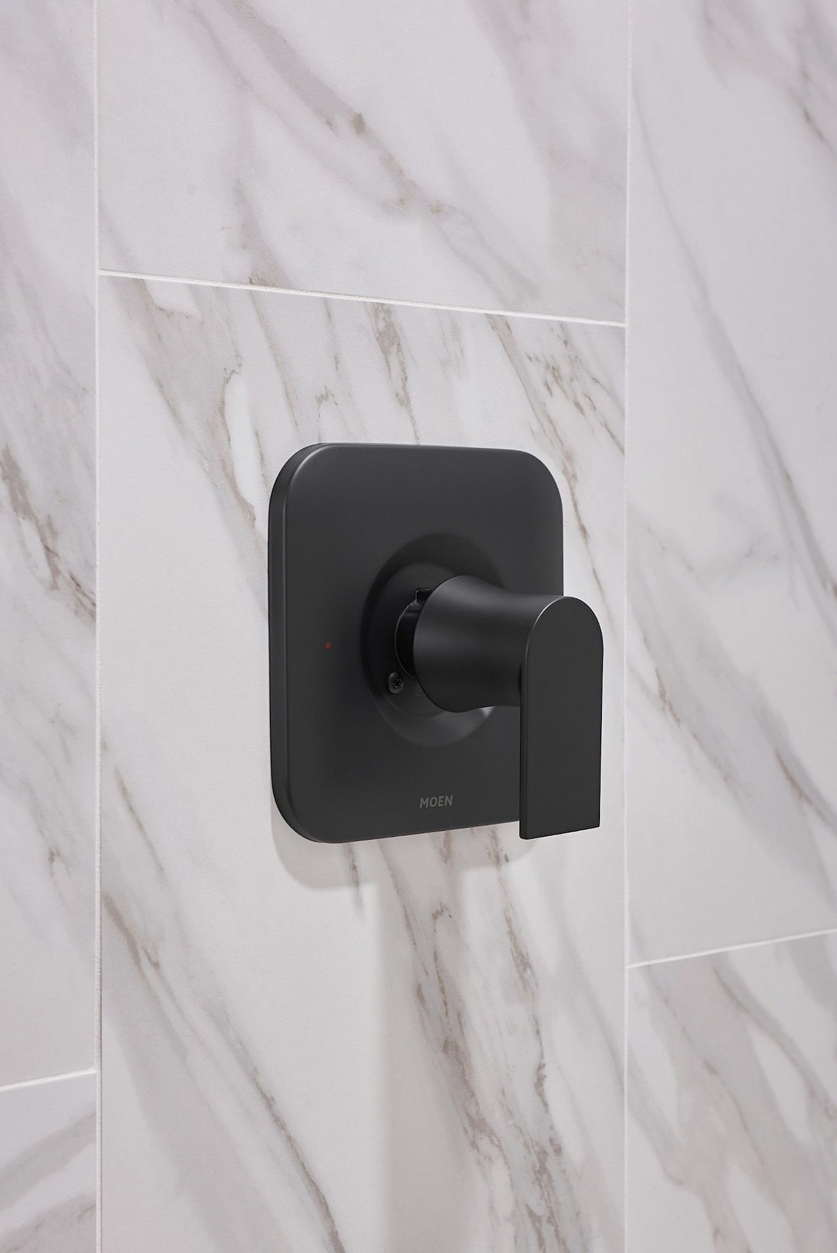 Matte black single-handle tub and shower trim with square escutcheon plate mounted on marble tile wall.