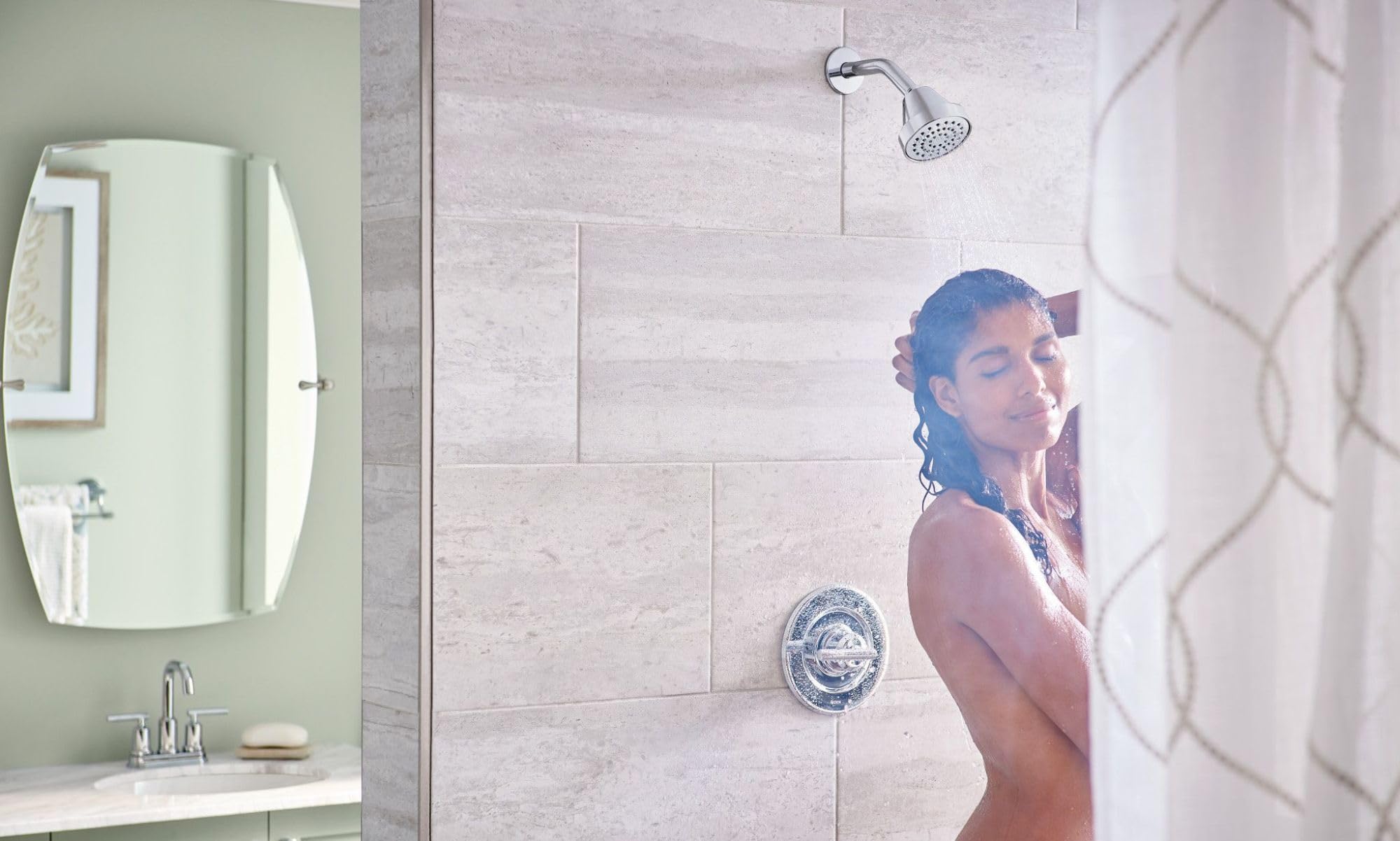 Chrome shower trim kit with single handle, showerhead, and body jet mounted on light gray tile wall.