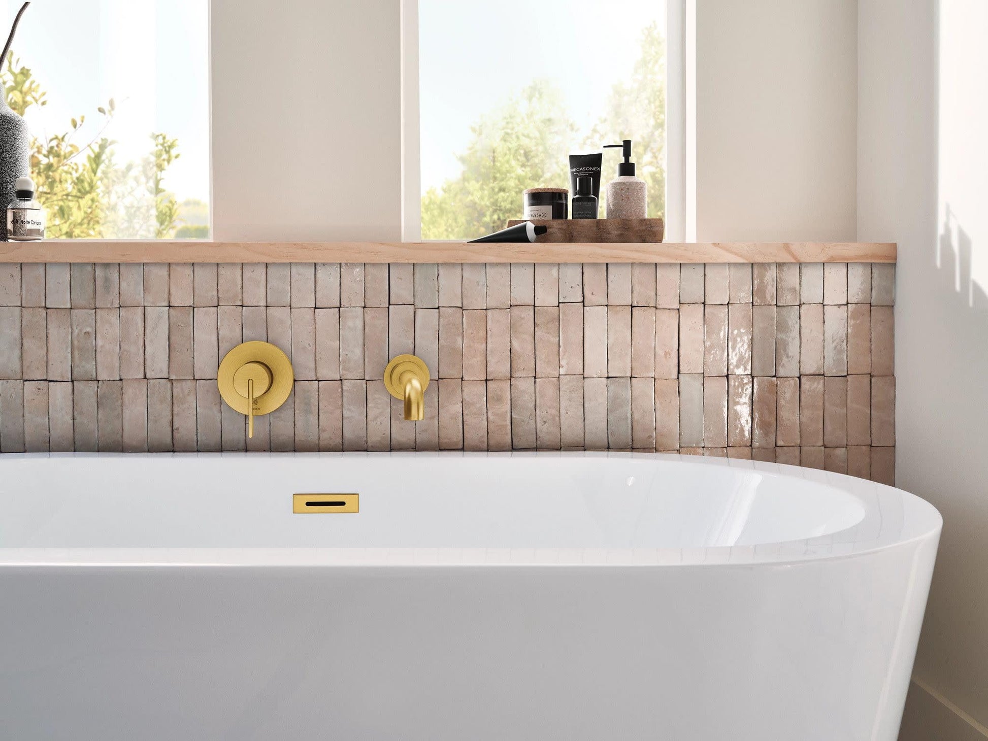 Brushed gold wall-mount tub faucet with single handle and spout installed above white freestanding bathtub.