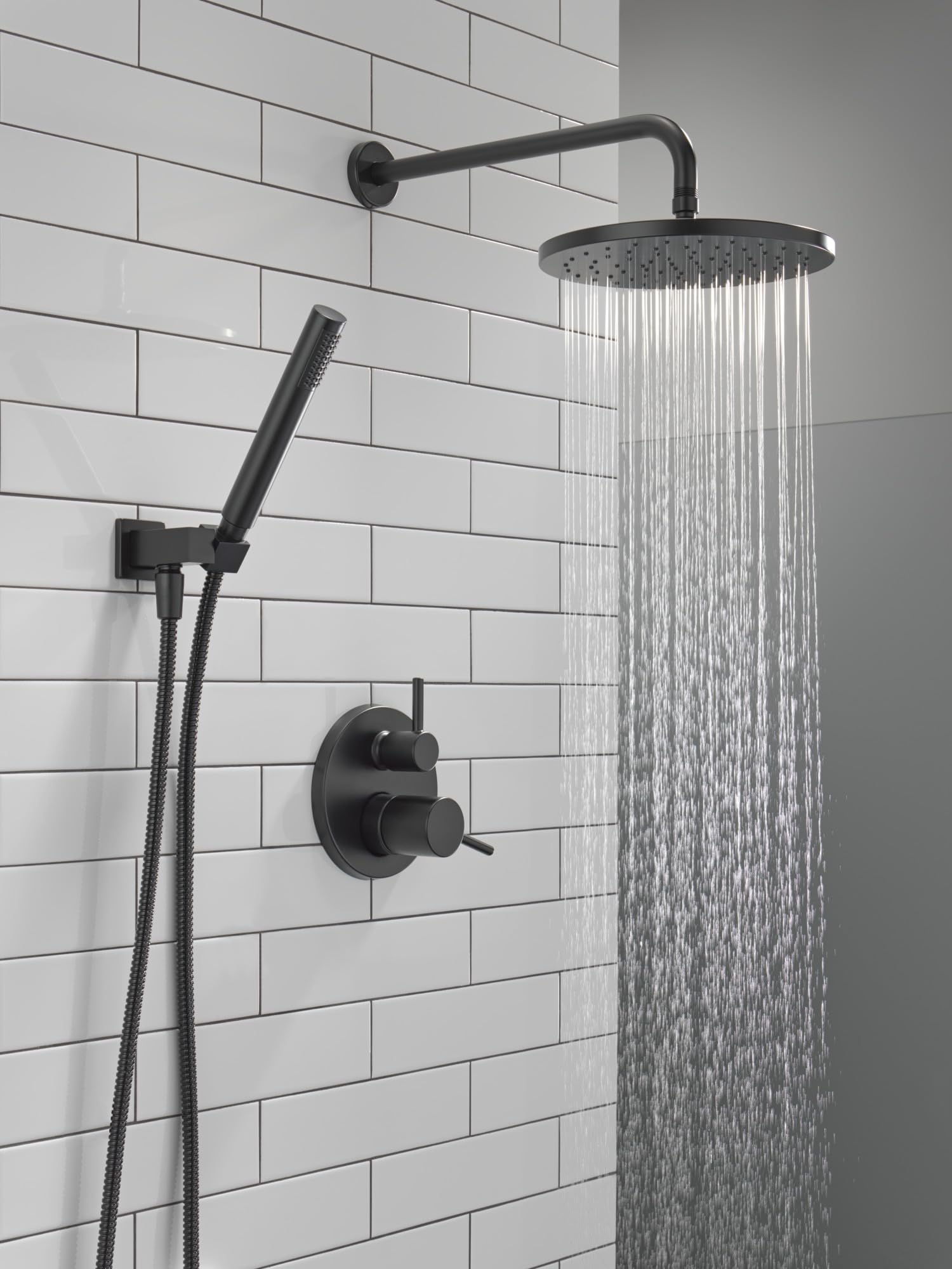 Matte black shower system with round raincan head, angled arm, handheld shower on hose, and dual-handle valve control mounted