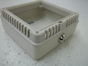 Beige plastic thermostat guard with ribbed sides, open top, and metal lock mechanism on front.