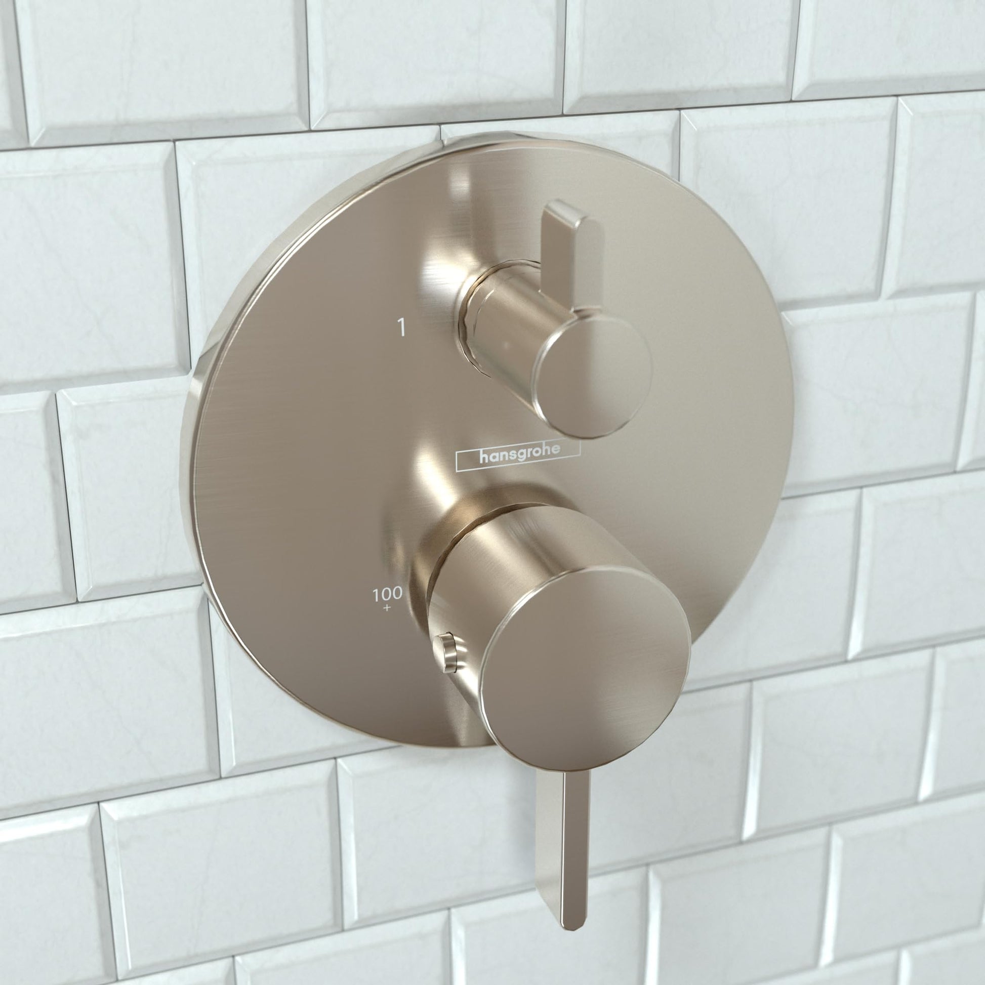 Brushed nickel thermostatic shower trim with round plate, upper control lever, and lower circular dial on white subway tile.