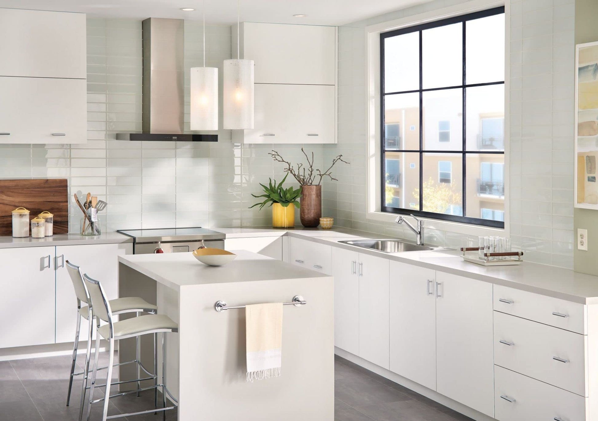 Moen stainless steel single-handle kitchen faucet with pullout sprayer installed at sink in white modern kitchen.