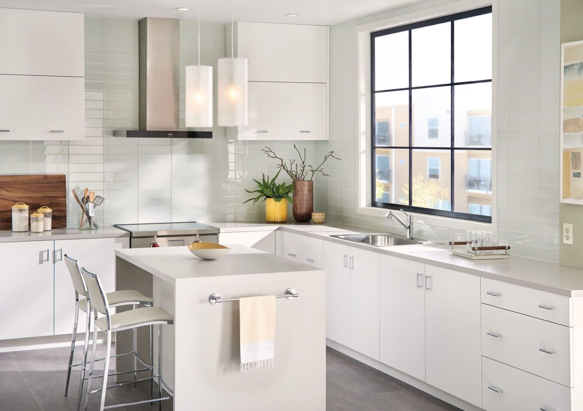 Moen stainless steel single-handle kitchen faucet with pullout sprayer installed at sink in white modern kitchen.