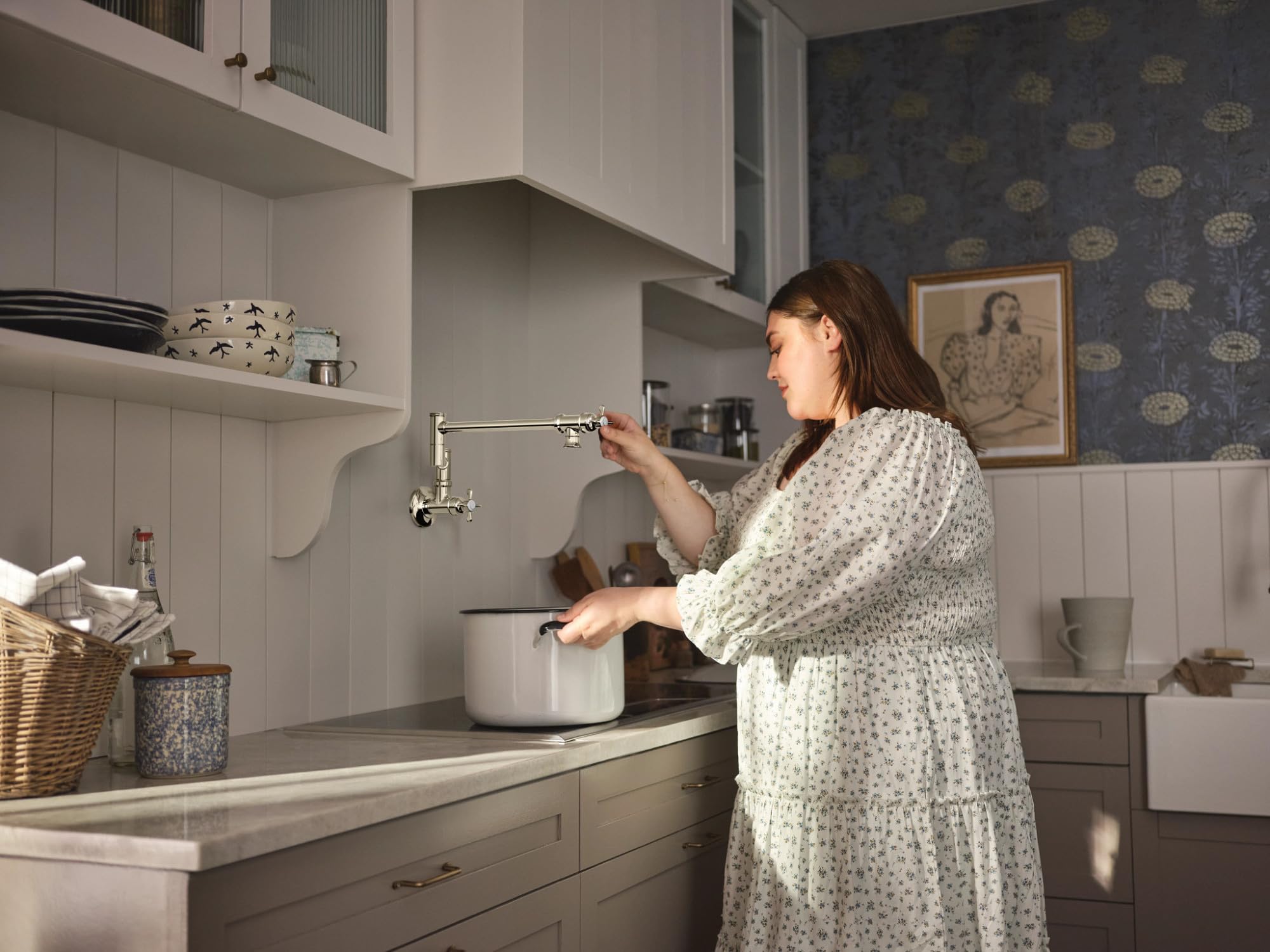 Polished nickel wall-mounted swing arm pot filler faucet with folding spout over kitchen countertop.
