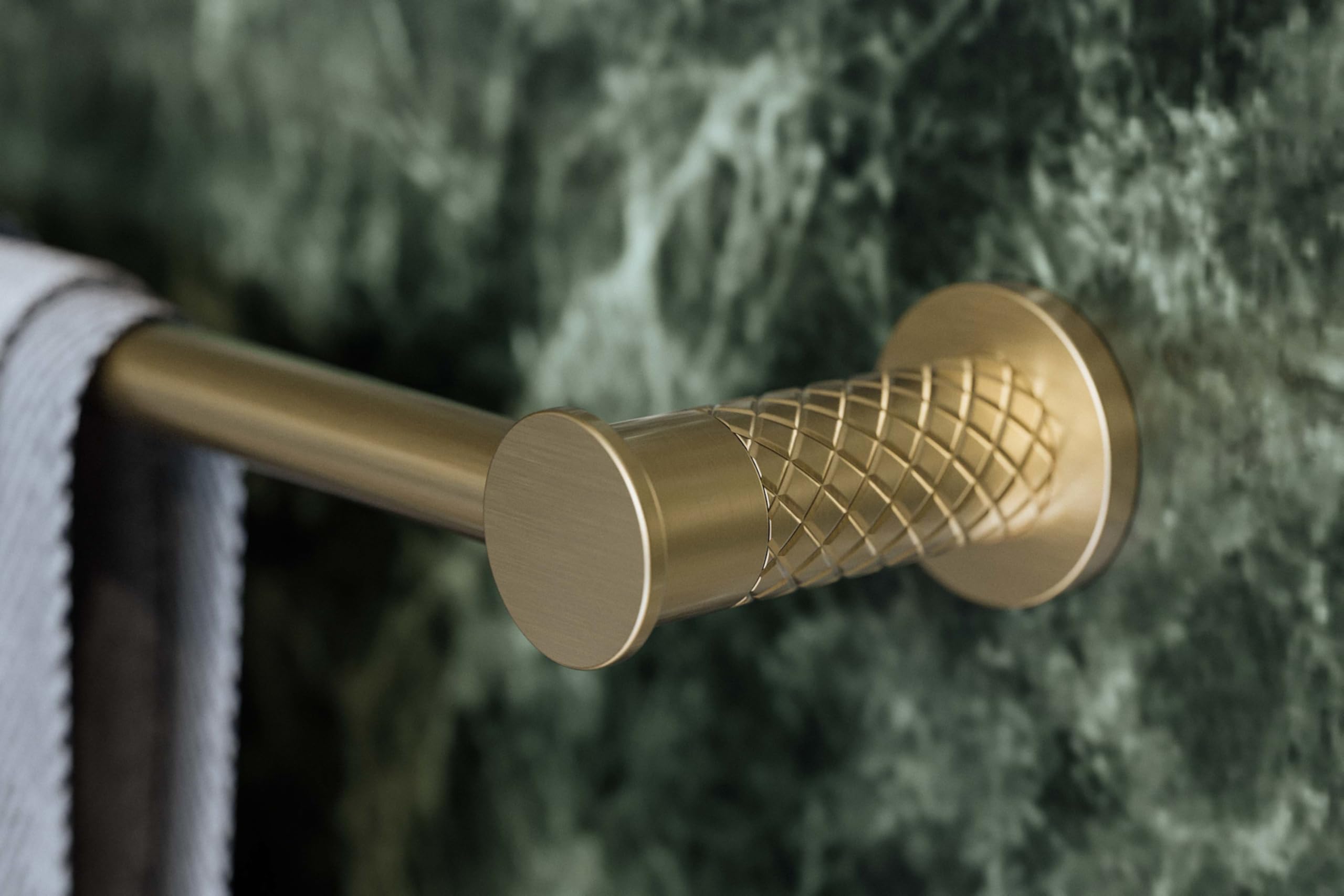 Antique gold towel bar with round mounting plates and quilted textured center section on green marble wall.